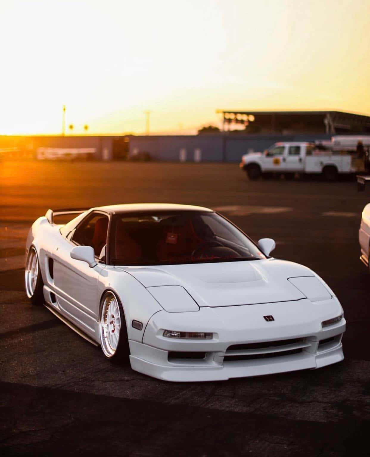 Honda Nsx 桌布 壁紙 — 一輛純白色的本田NSX跑車在空蕩蕩的瀝青停車場上，於金色夕陽下閃閃發光。