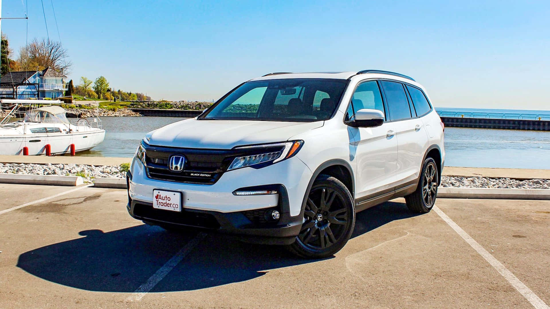 Honda Pilot 桌布 壁紙 — 一輛純白色的本田Pilot SUV停放在陽光明媚的海濱地段，旁邊停靠著一艘帆船。