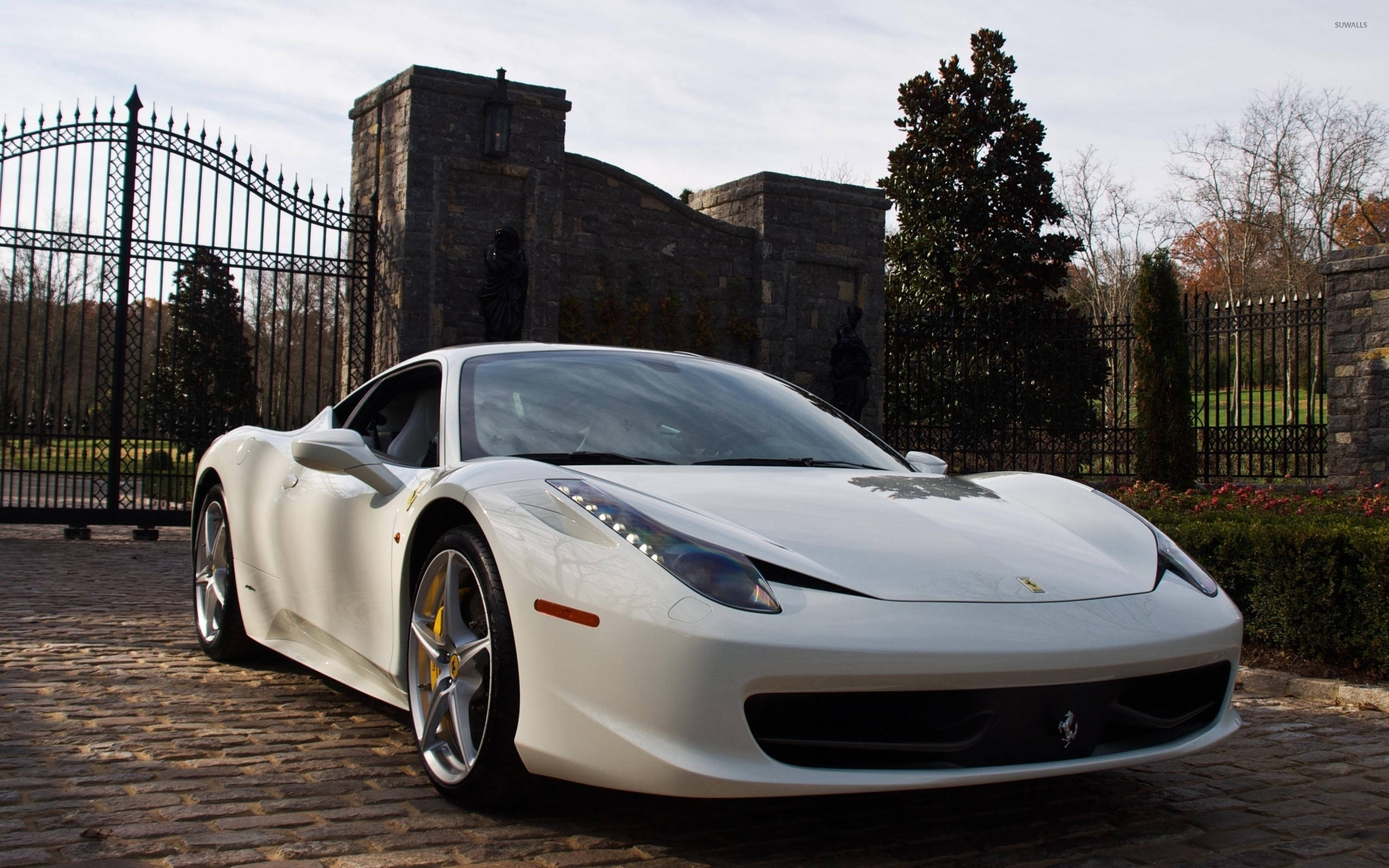 white ferrari 桌布 壁紙 — 一輛純白色的法拉利458停泊在石門前鵝卵石車道上，旁邊是修剪整齊的花園。