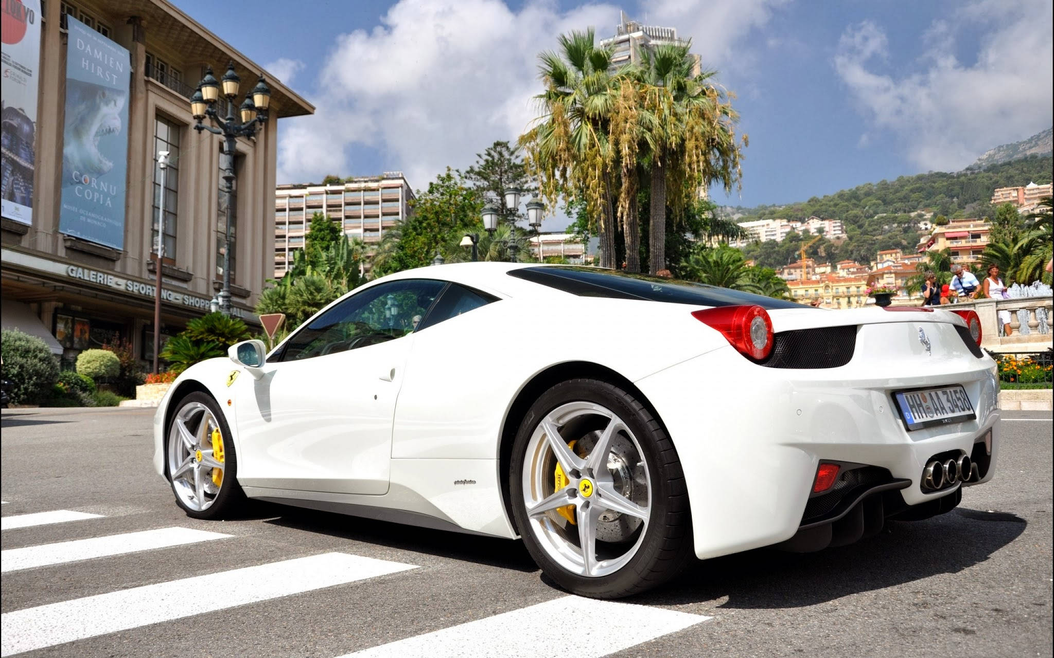 white ferrari 桌布 壁紙 — 一輛純白色的法拉利跑車停放在陽光明媚的街道上，背景有棕櫚樹和地中海建築。