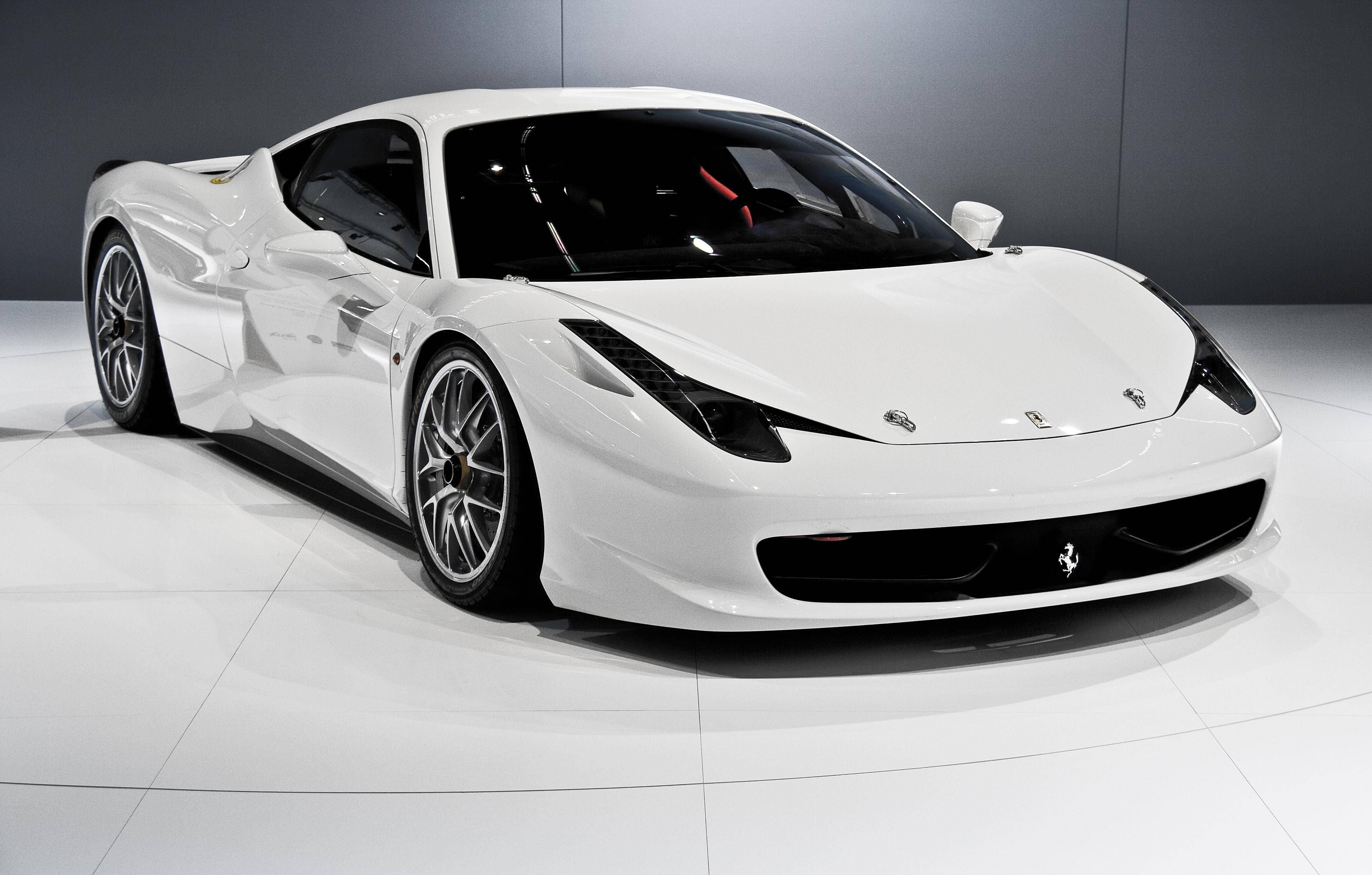 white ferrari 桌布 壁紙 — 一輛純白色的法拉利跑車在攝影棚燈光下，在反光的白色地板上，以深灰色牆壁為背景閃閃發光。