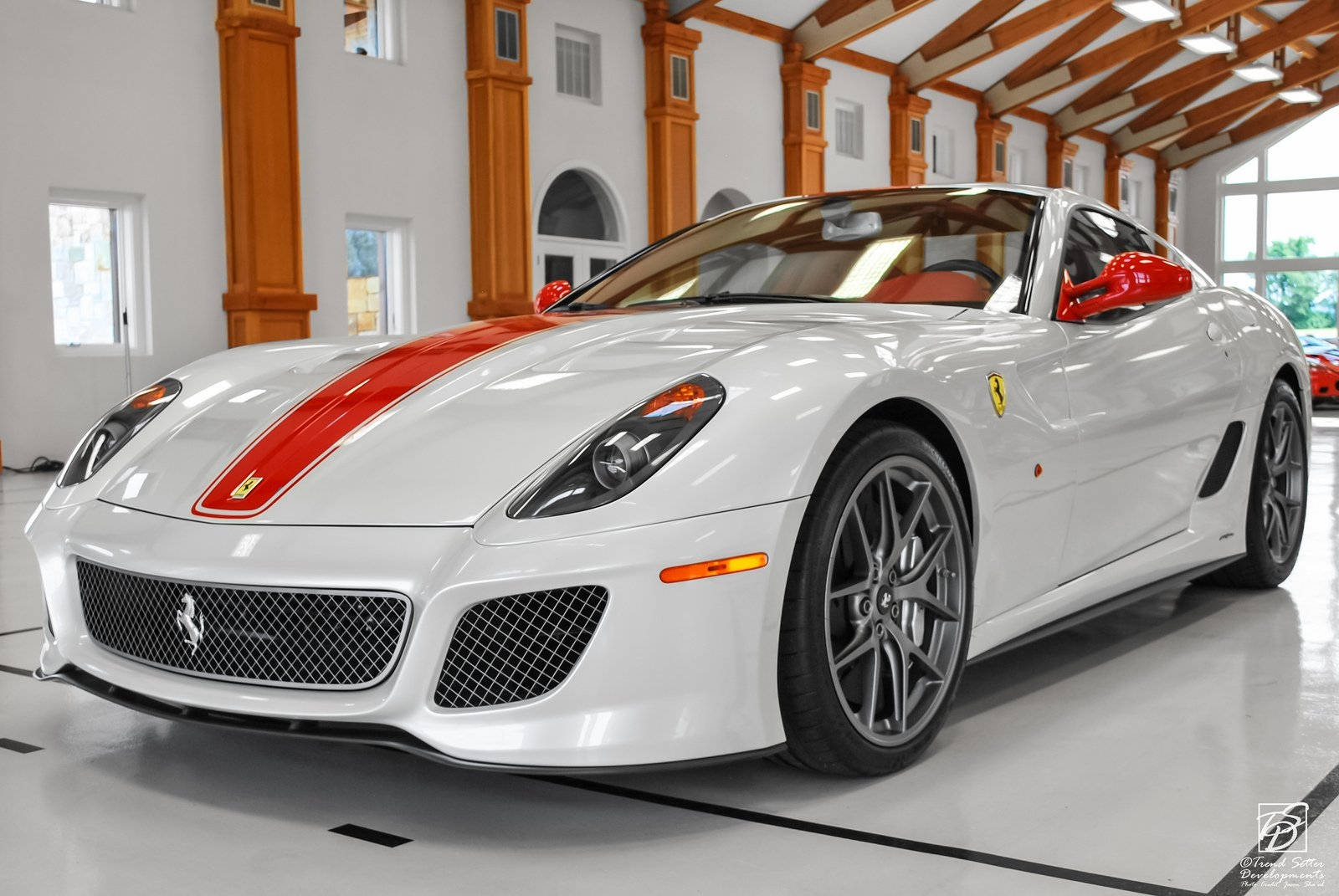 white ferrari 桌布 壁紙 — 一輛純白色的法拉利跑車帶有紅色賽車條紋，在寬敞的木樑車庫中閃閃發光。