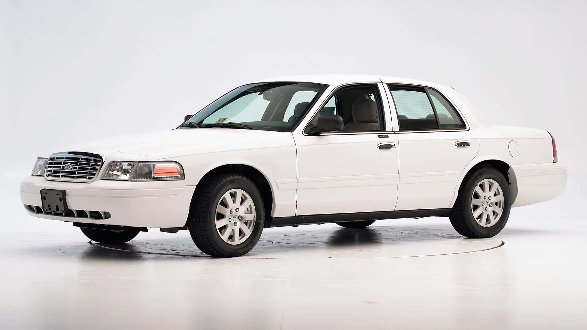 Ford Crown Victoria 桌布 壁紙 — 一輛純白色的福特皇冠維多利亞轎車在明亮的攝影棚中展示，線條簡潔，表面反光。
