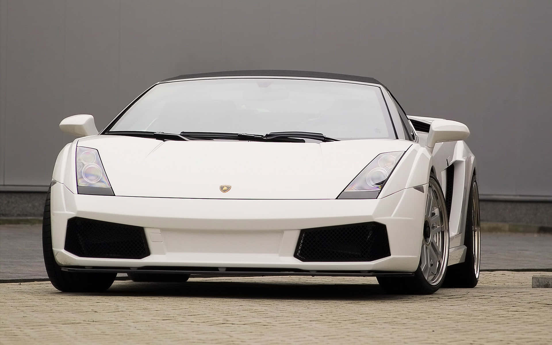 Lamborghini Gallardo 桌布 壁紙 — 一輛純白色的藍寶堅尼 Gallardo Spyder 停放在鵝卵石地面上，背景是簡約的灰色牆壁。