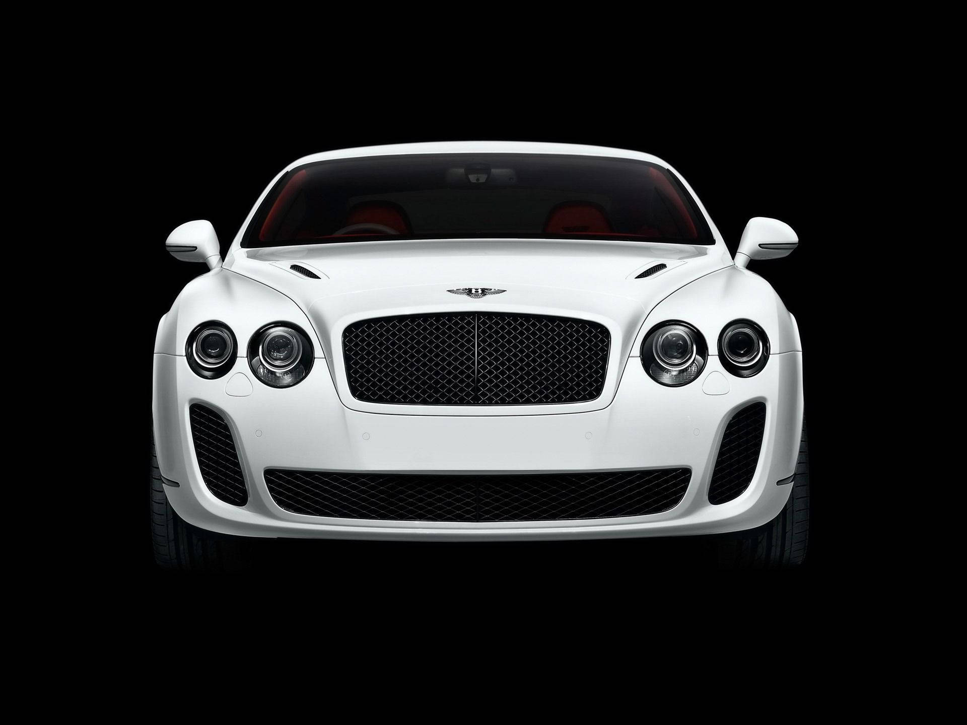 黑白 桌布 壁紙 — 一輛純白色的賓利 Continental Supersports 在純黑背景前正面朝前，其標誌性水箱護罩和圓形頭燈在攝影棚燈光下閃閃發光。