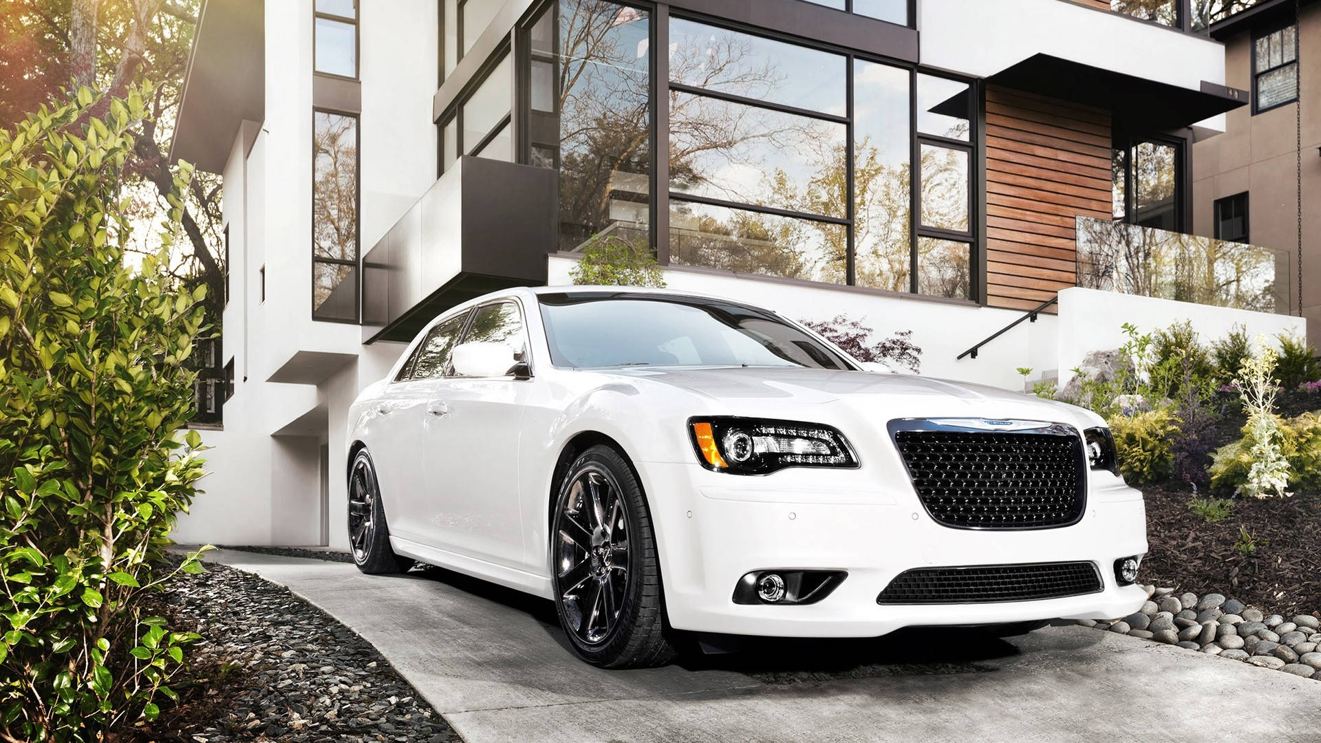 Chrysler 桌布 壁紙 — 一輛純白色豪華轎車配黑色輪圈，停放在現代混凝土車道上，旁邊是一座時尚的玻璃和木屋。