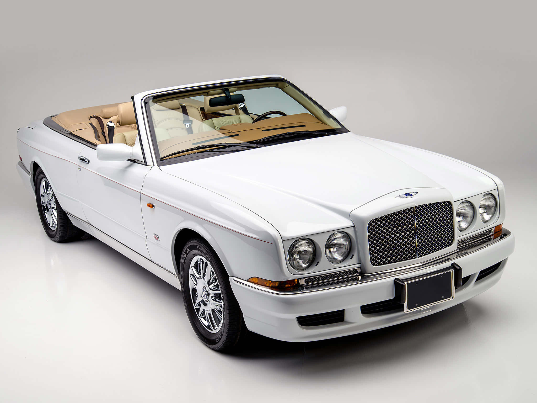 Bentley Azure 桌布 壁紙 — 一輛純白色賓利敞篷車，配備淺褐色皮革內裝，在極簡主義的攝影棚環境中展示。