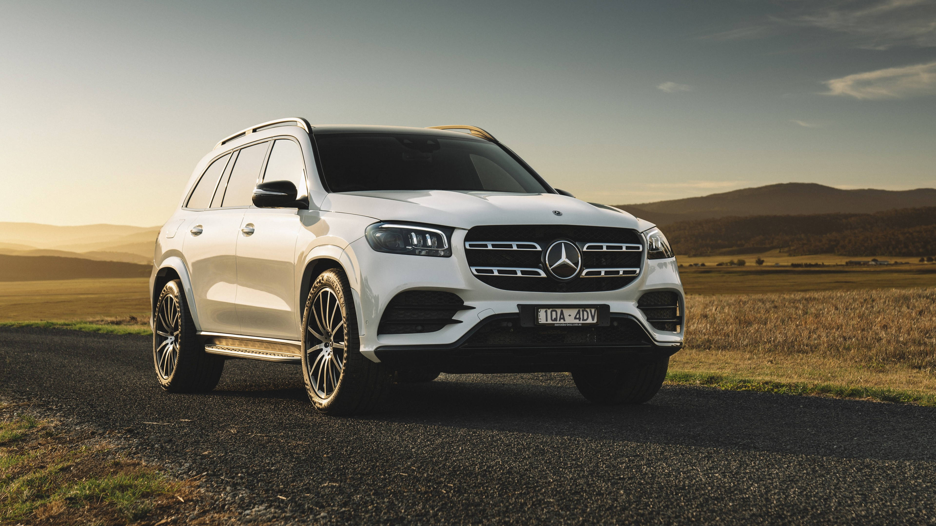 Mercedes 桌布 壁紙 — 一輛純白色賓士GLS SUV停在碎石路上，正值黃金時刻，背景是連綿起伏的山丘。