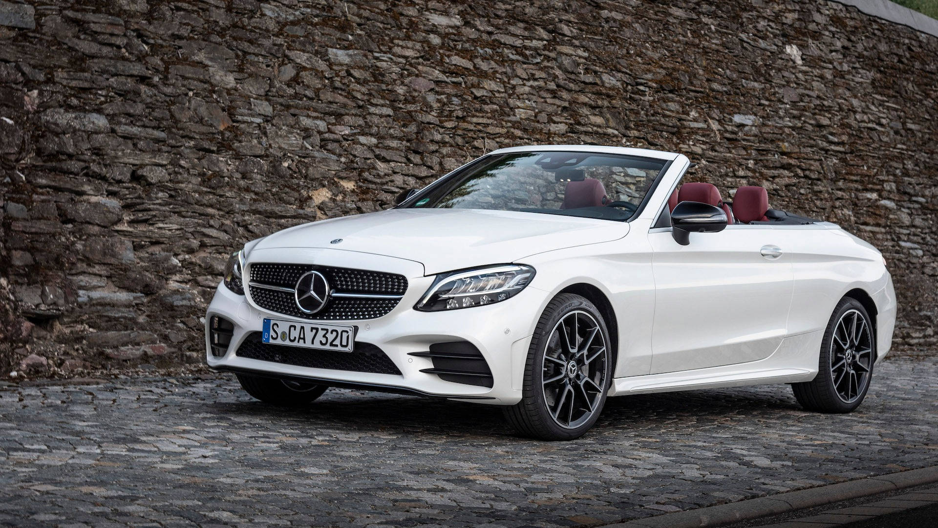 Mercedes Benz C300 桌布 壁紙 — 一輛純白色賓士敞篷車停泊在鵝卵石街道上，旁邊是粗糙的石牆。