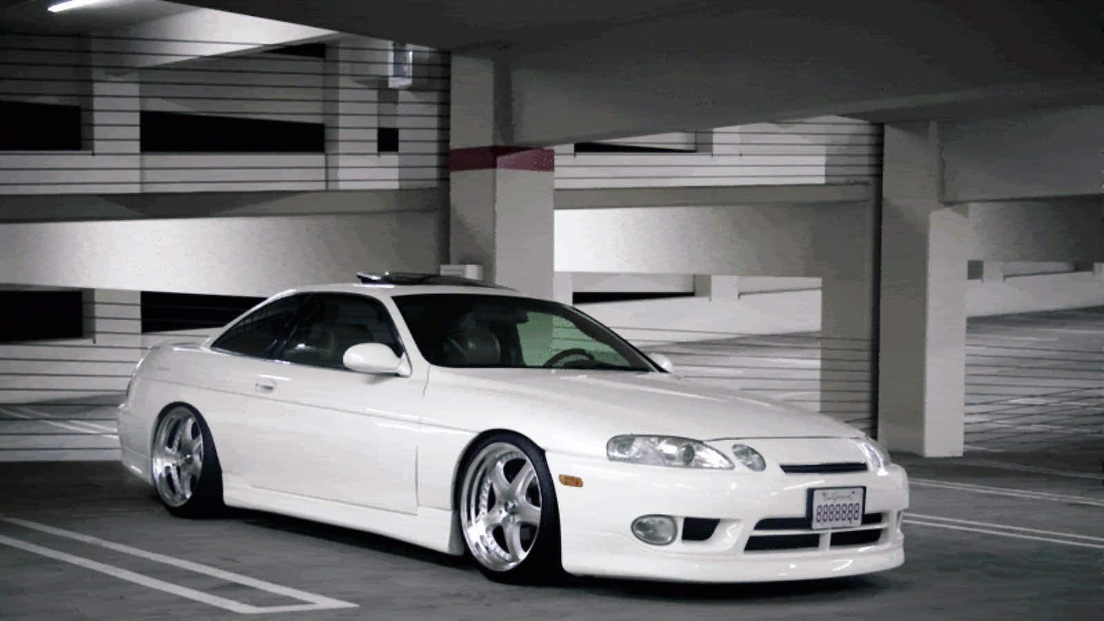 Lexus Sc 300 桌布 壁紙 — 一輛純白色運動型轎跑車，配備定制輪圈，停放在現代多層停車場的人工照明下。