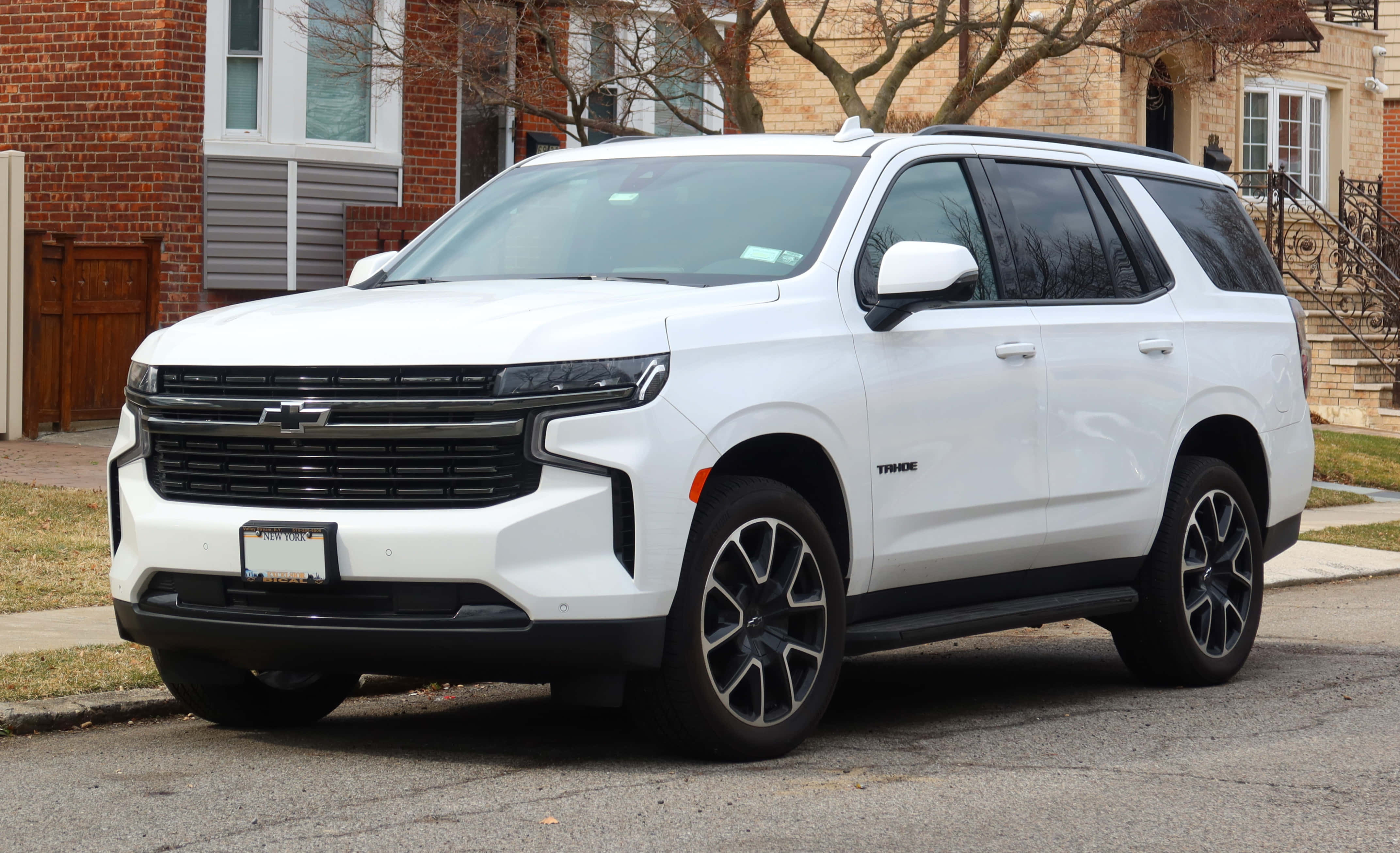 Chevrolet 桌布 壁紙 — 一輛純白色雪佛蘭Tahoe SUV停放在住宅街道上，背景有磚房和光禿禿的樹木。