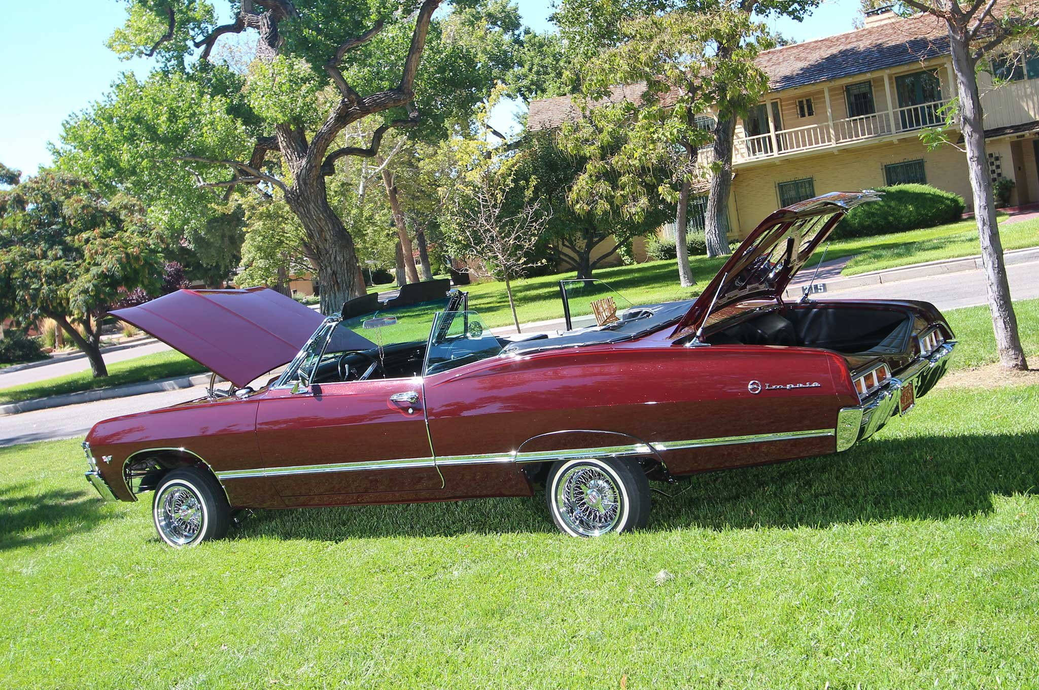 chevrolet impala 1967 桌布 壁紙 — 一輛經典栗色敞篷車，引擎蓋和後車廂打開，停放在陽光普照的綠色草坪上，旁邊是一棟黃色房子。