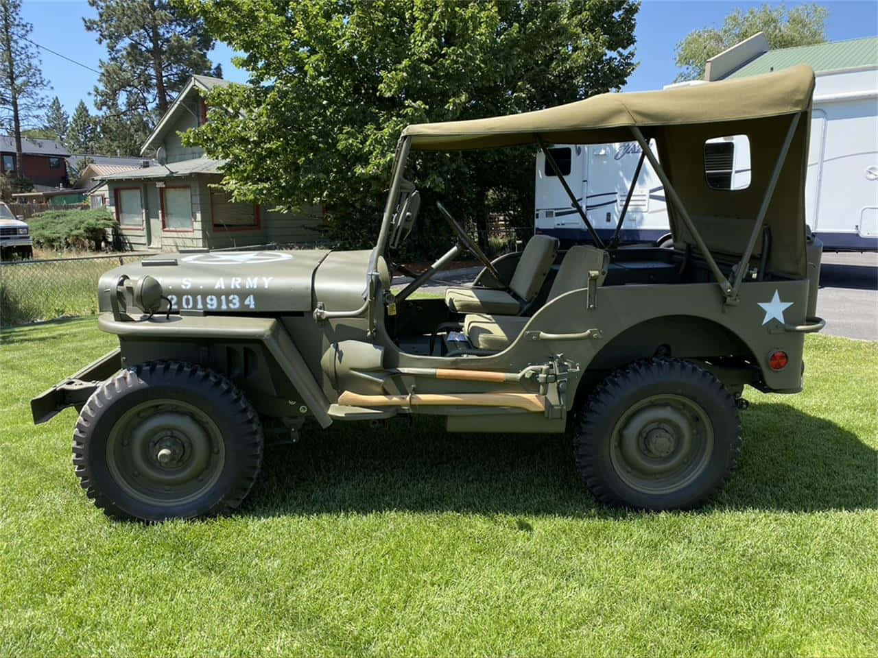 Jeep Willys 桌布 壁紙 — 一輛經典橄欖綠色軍用吉普車，帶帆布頂篷，停在鮮綠的草地上，陽光明媚。