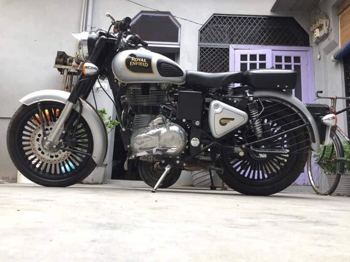 經典的Royal Enfield機車停在混凝土車道上，旁邊有一輛自行車。 — 機車 壁紙