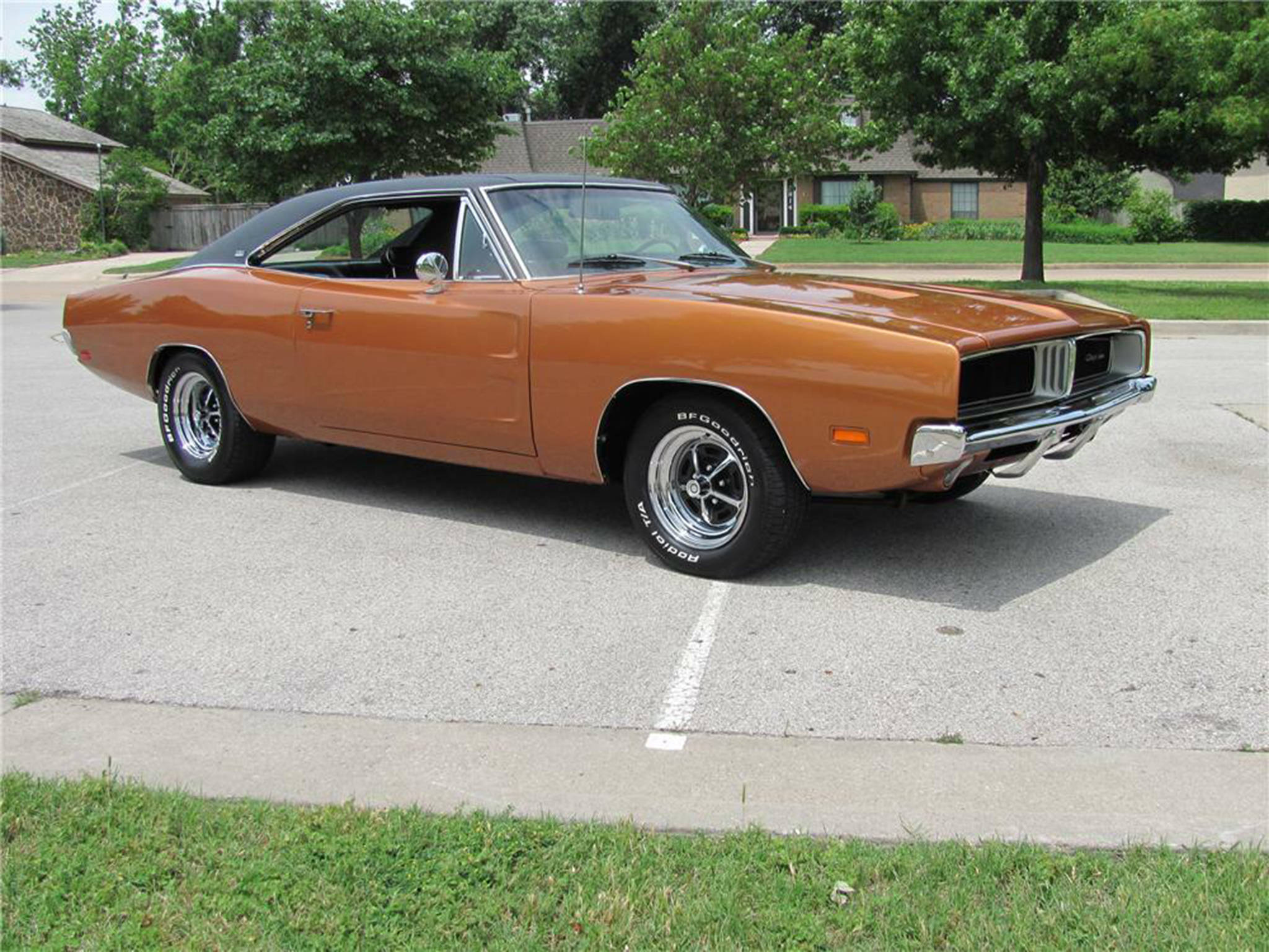 Charger 桌布 壁紙 — 一輛經典的橙色道奇Charger，帶黑色乙烯基車頂，停在陽光明媚的郊區街道上。