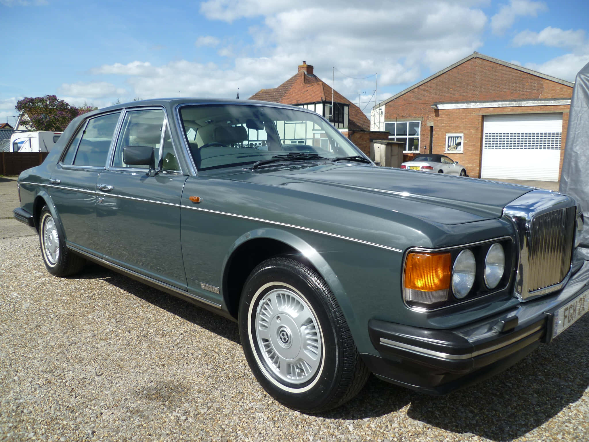 Bentley Eight 桌布 壁紙 — 一輛經典的綠色賓利轎車在明亮的日光下閃閃發光，停在磚房附近的碎石車道上。