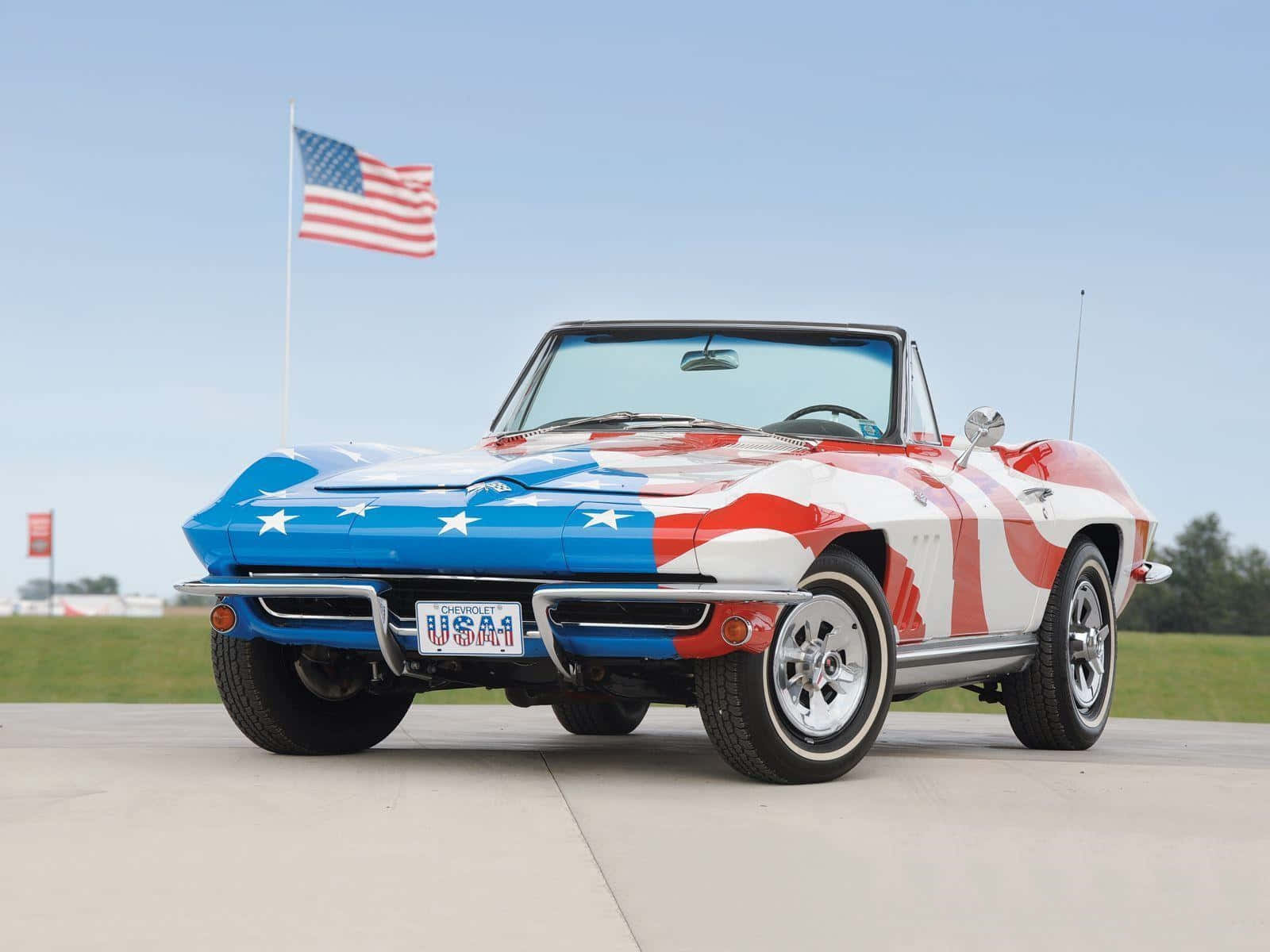 chevy 桌布 壁紙 — 一輛經典的美國敞篷跑車，塗有愛國的紅、白、藍星條紋，背景中飄揚著美國國旗。