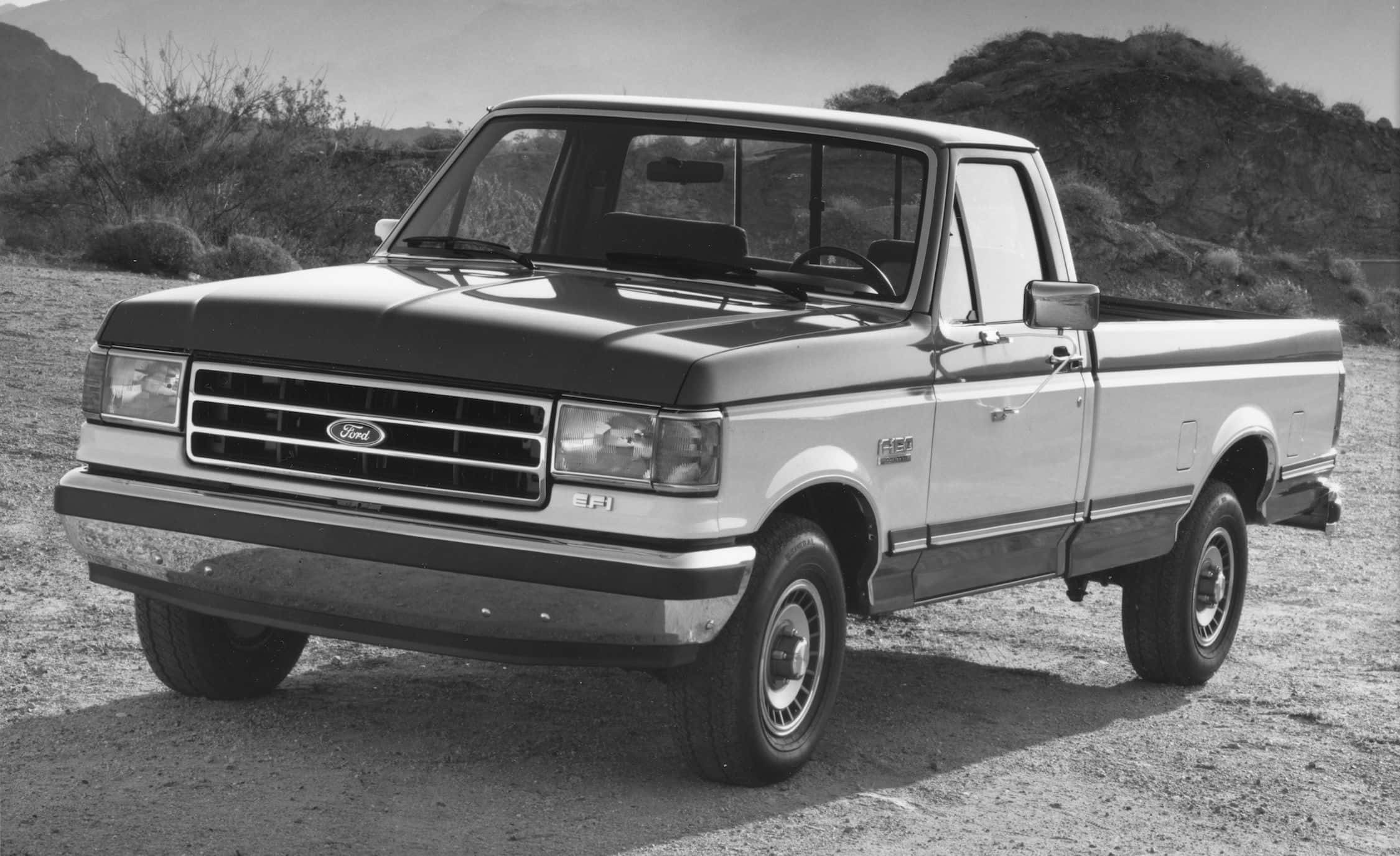 Ford Truck 桌布 壁紙 — 一輛經典福特皮卡車停在塵土飛揚的沙漠道路上，背景是崎嶇的山丘。