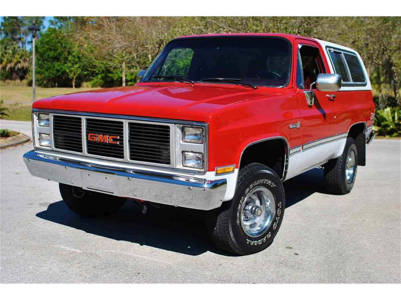 Gmc Jimmy 桌布 壁紙 — 一輛經典紅白相間的GMC皮卡車停在柏油路面上，背景有樹木，在明亮的陽光下。