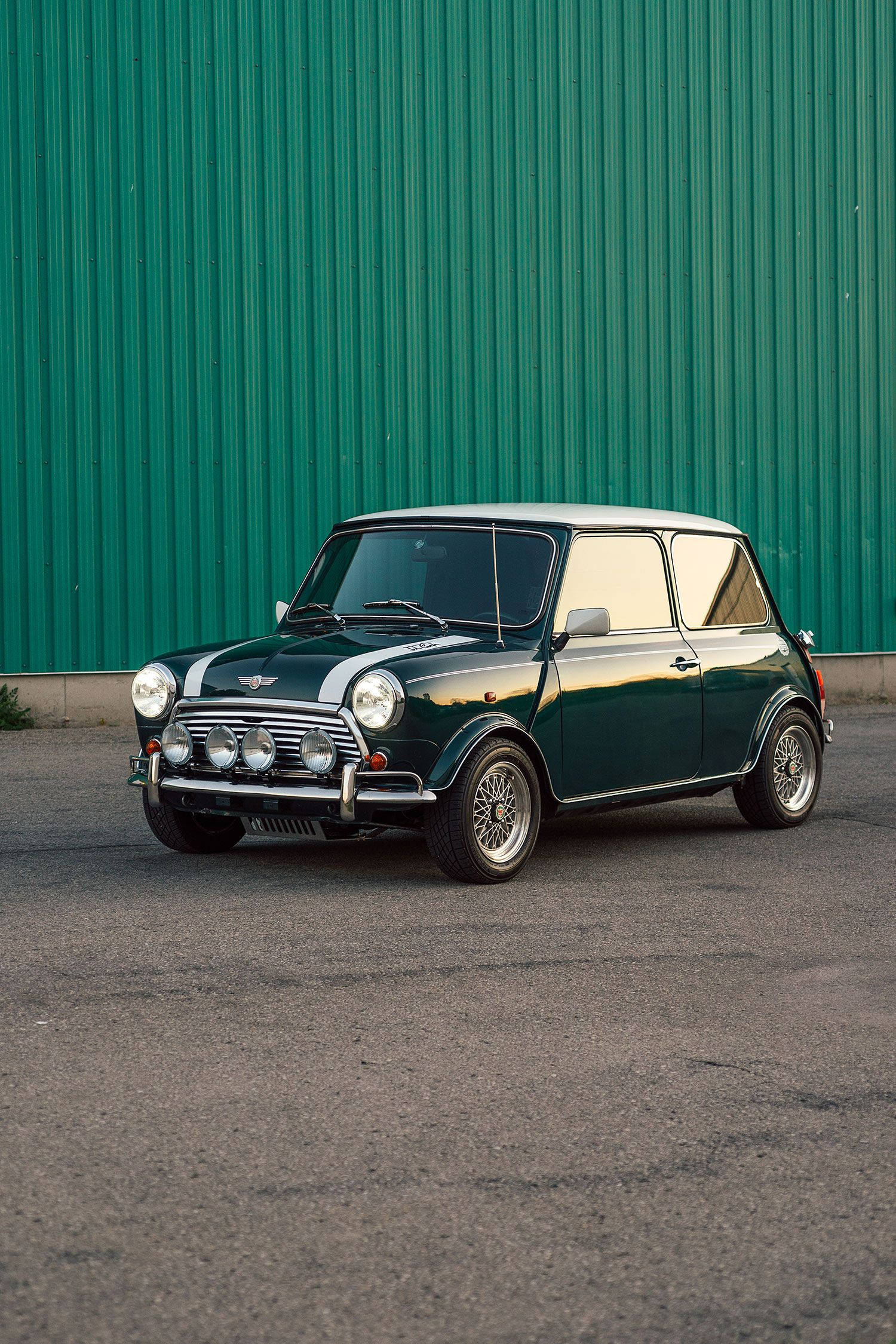 Phone Screen 桌布 壁紙 — 一輛經典綠色Mini Cooper，白色車頂和賽車條紋，停在充滿活力的綠色波紋金屬牆前。