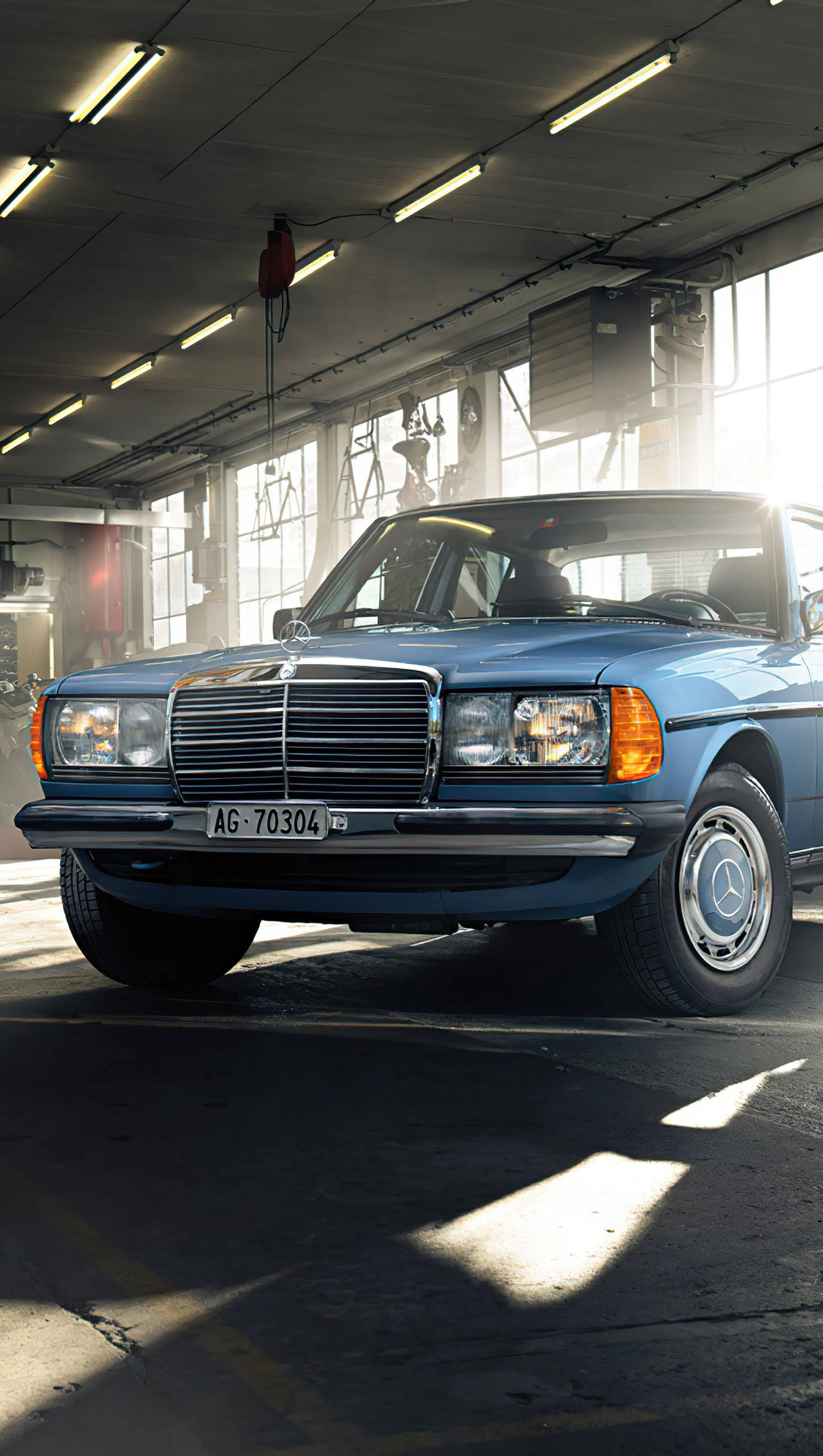 Mercedes 桌布 壁紙 — 一輛經典藍色賓士轎車在車庫高窗射入的明亮陽光下閃閃發光。