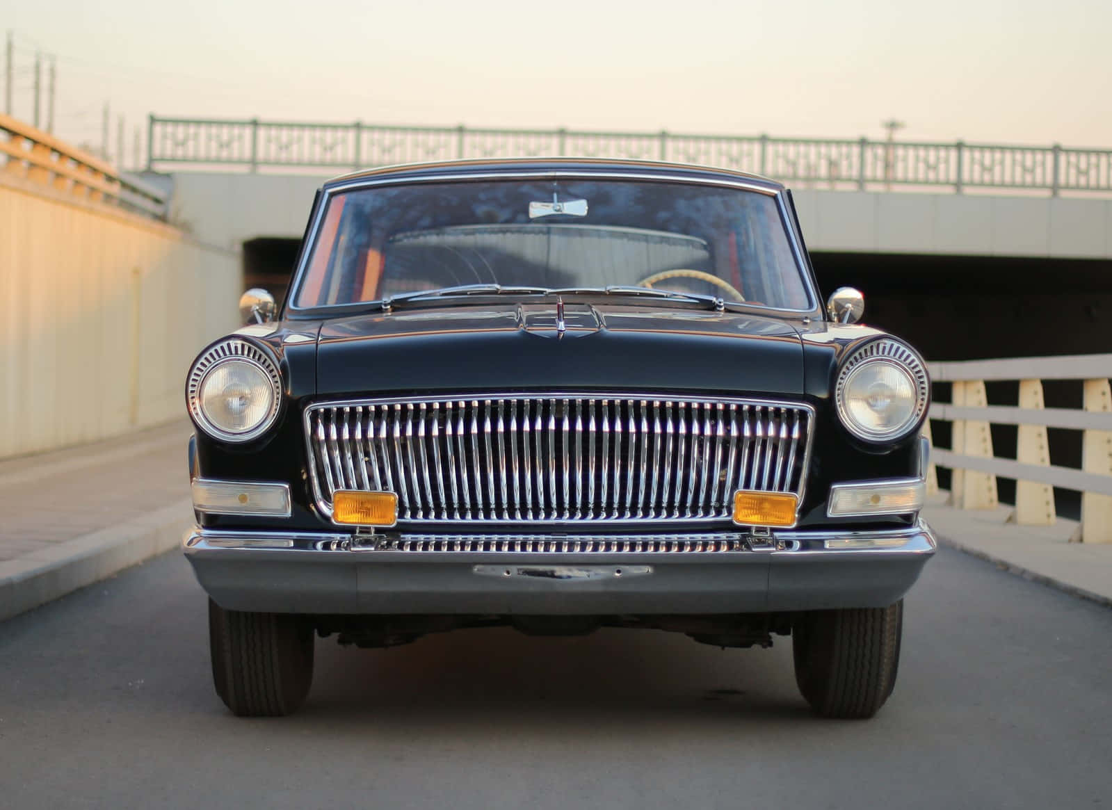 Hongqi 桌布 壁紙 — 一輛經典黑色汽車，帶有鍍鉻格柵和圓形頭燈，在黃金時段面向橋樑前方。