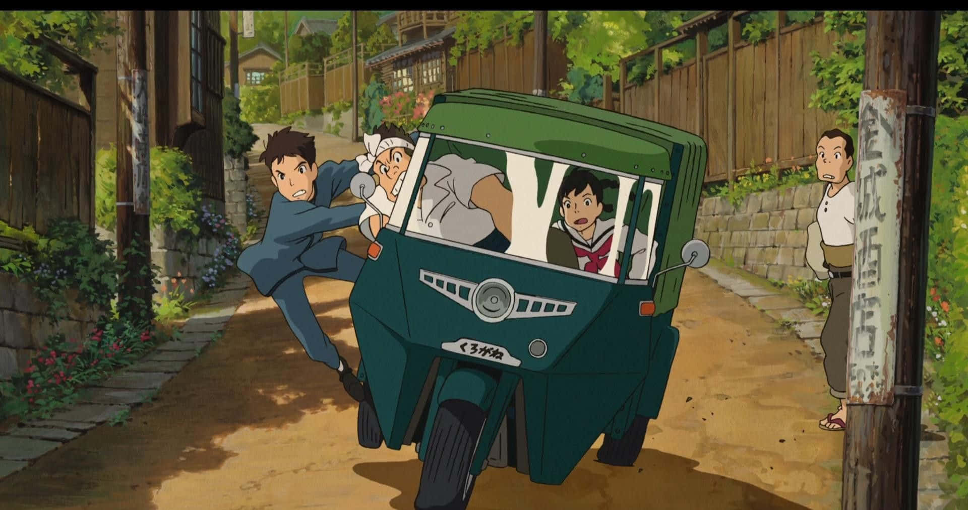 來自紅花坂 桌布 壁紙 — 一輛綠色三輪車在陽光明媚的日本村莊街道上飛馳，一個男孩推著它，兩個孩子驚訝地看著。