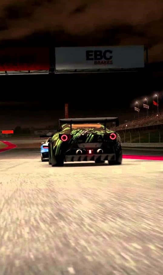 Grid Autosport 桌布 壁紙 — 一輛綠色和黑色的賽車，帶有發光的紅色尾燈，在體育場燈光下的夜間賽道上飛馳。