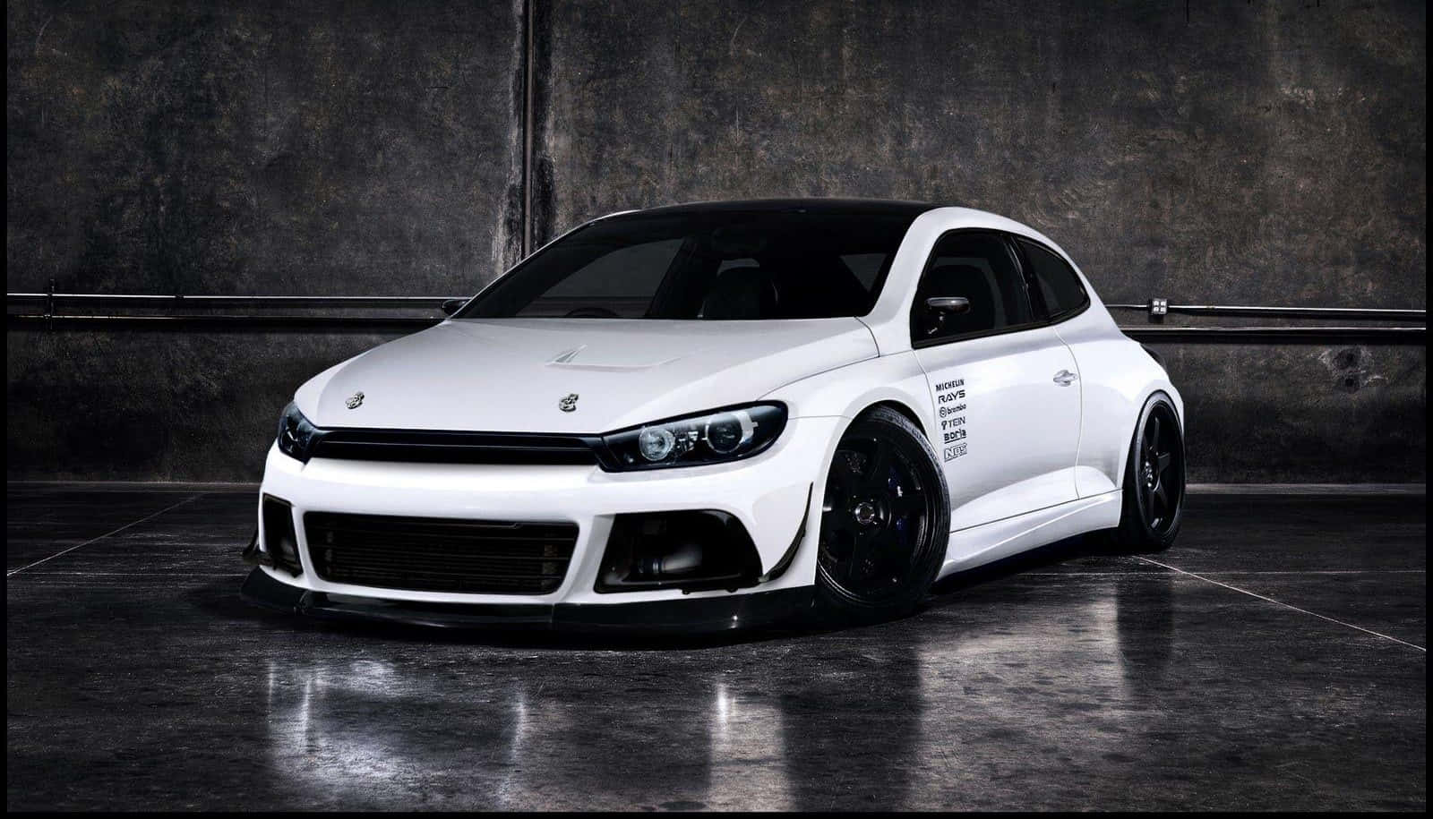 Tuned Car 桌布 壁紙 — 一輛線條流暢的白色改裝福斯Scirocco，帶有黑色飾件和訂製輪圈，停放在光線昏暗、混凝土地面反光的工業車庫內。