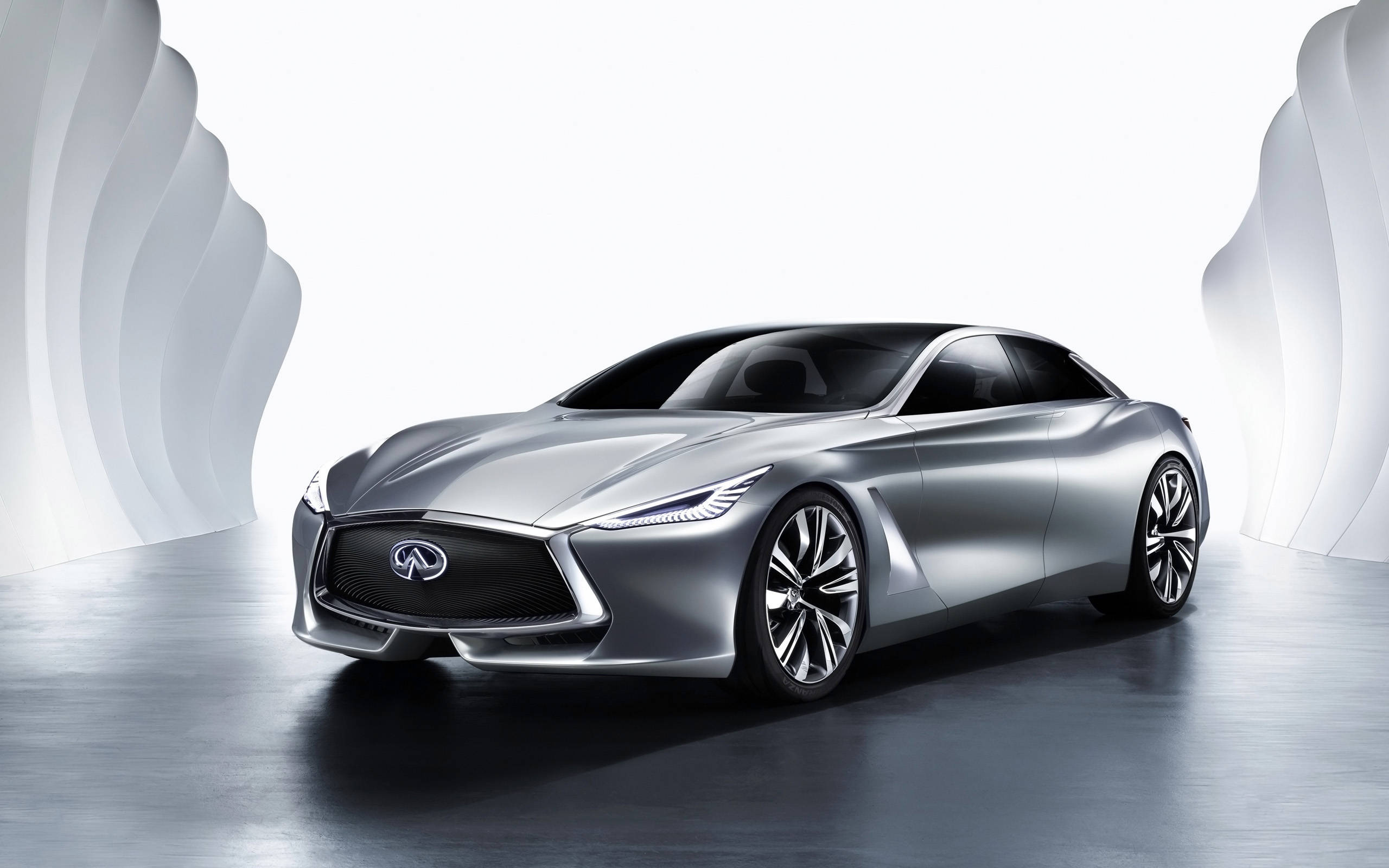 Infiniti 桌布 壁紙 — 一輛線條銳利、車頭燈閃亮的時尚銀色概念車，展示在彎曲的白色牆壁之間，地板具有反射效果。