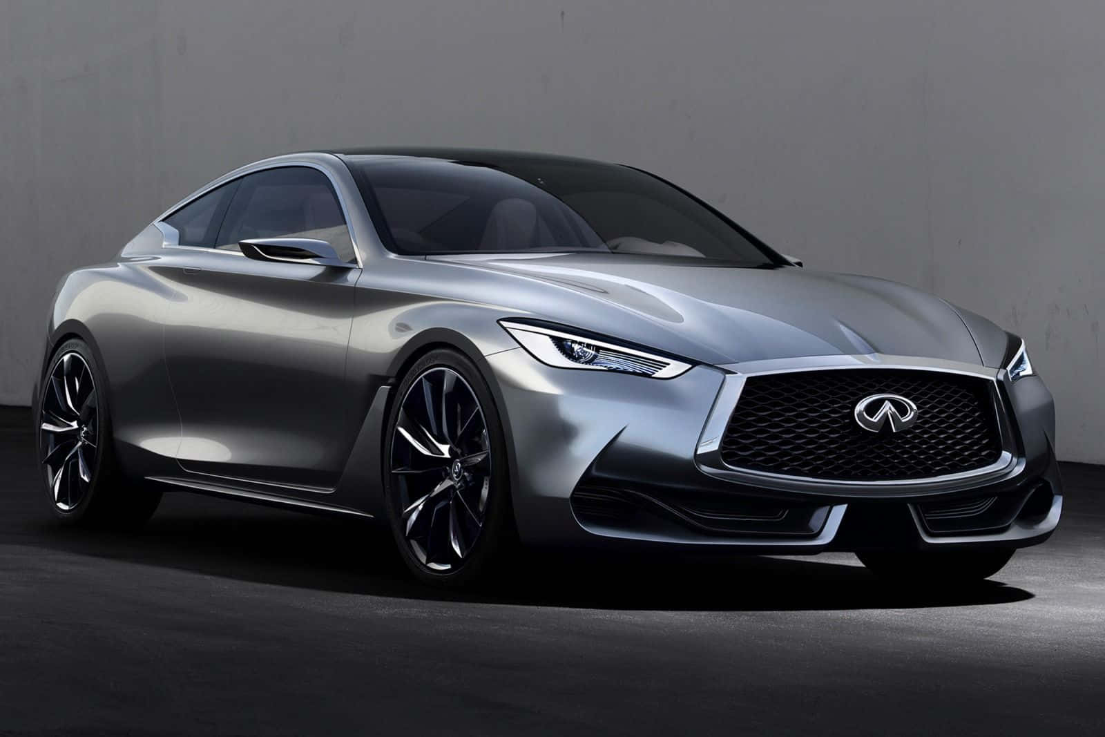 Infiniti Q60 桌布 壁紙 — 一輛線條銳利、頭燈閃亮的時尚銀色 Infiniti 概念車，在極簡灰色工作室背景前蓄勢待發。