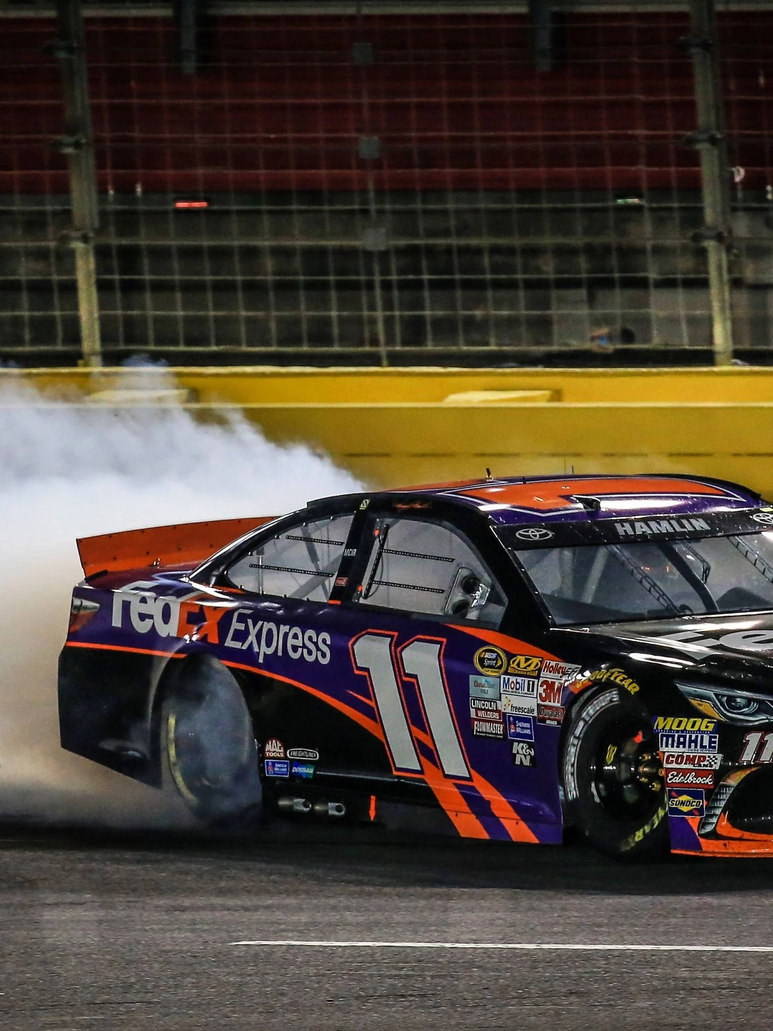 Denny Hamlin 桌布 壁紙 — 一輛編號11的FedEx Express賽車在夜間賽道上進行燒胎，揚起濃厚的白色煙霧。