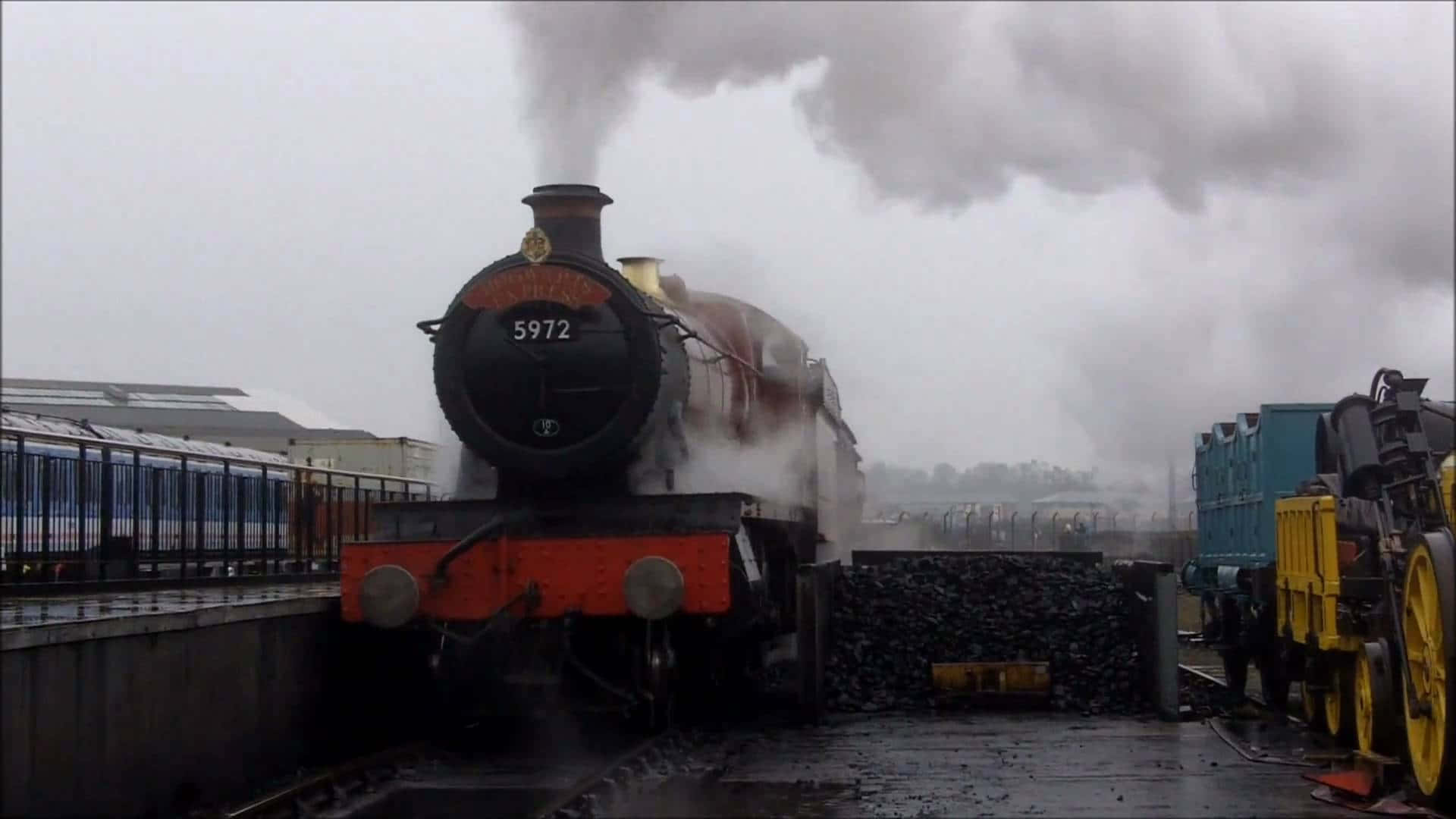 Hogwarts Express 桌布 壁紙 — 一輛編號5972的復古蒸汽火車頭在陰天之下，停靠在濕漉漉的火車站月台上，噴出濃濃的煙霧。