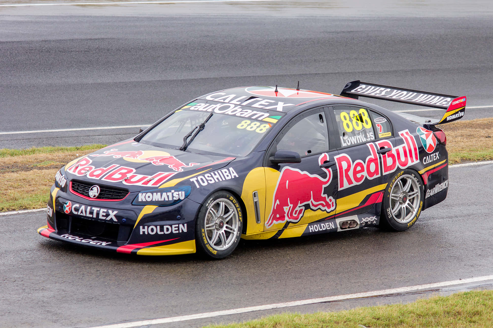 Car Racing 桌布 壁紙 — 一輛編號888的Red Bull Racing Holden V8 Supercar在多雲的天空下沿著濕滑的賽道疾馳。