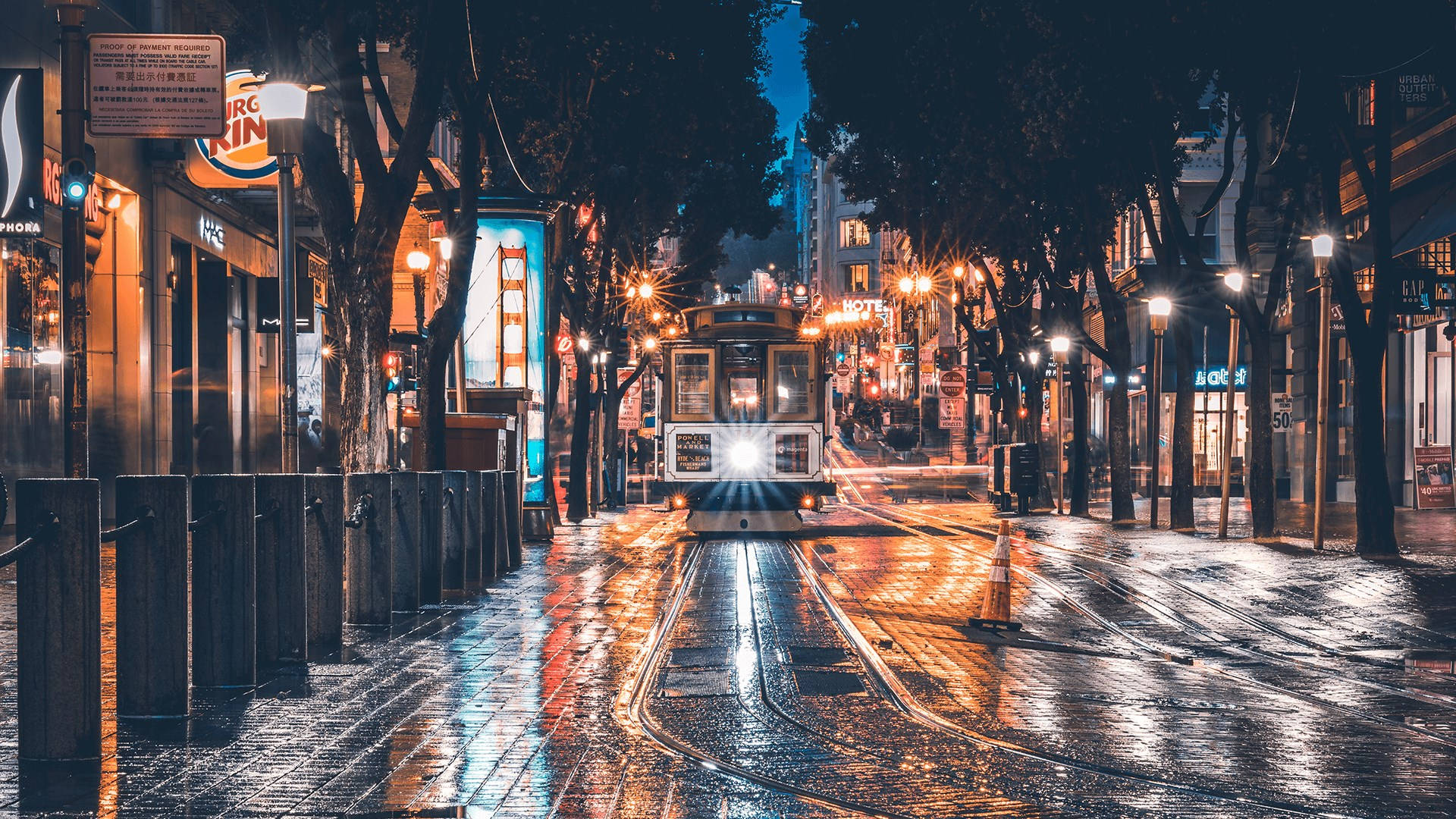 Outlook 桌布 壁紙 — 一輛纜車在夜間沿著濕漉漉的舊金山街道滑行，車頭燈穿透濕滑的路面，閃爍的街燈在波光粼粼的水坑中反射。