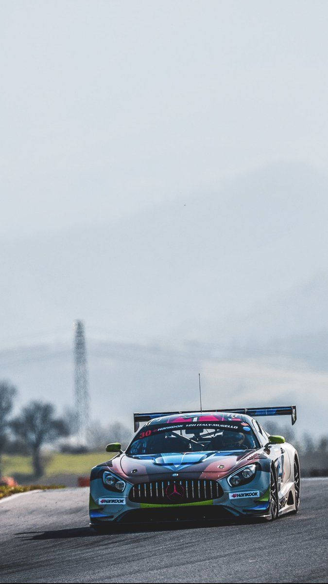 Racing 桌布 壁紙 — 一輛色彩繽紛的賽車在陰天潮濕的賽道上飛馳。
