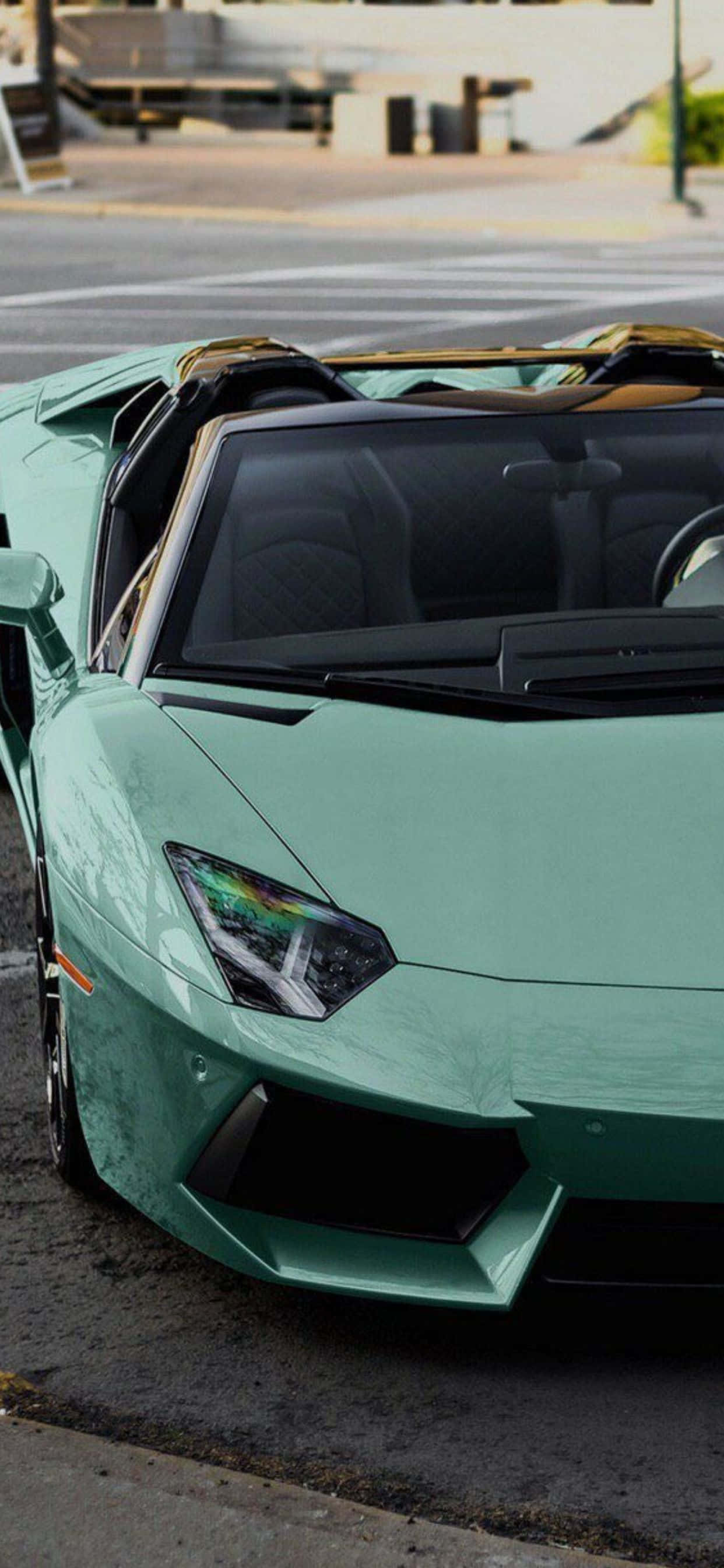 Lamborghini Phone 桌布 壁紙 — 一輛薄荷綠色的藍寶堅尼 Aventador 敞篷跑車停放在城市街道上，車頂敞開。
