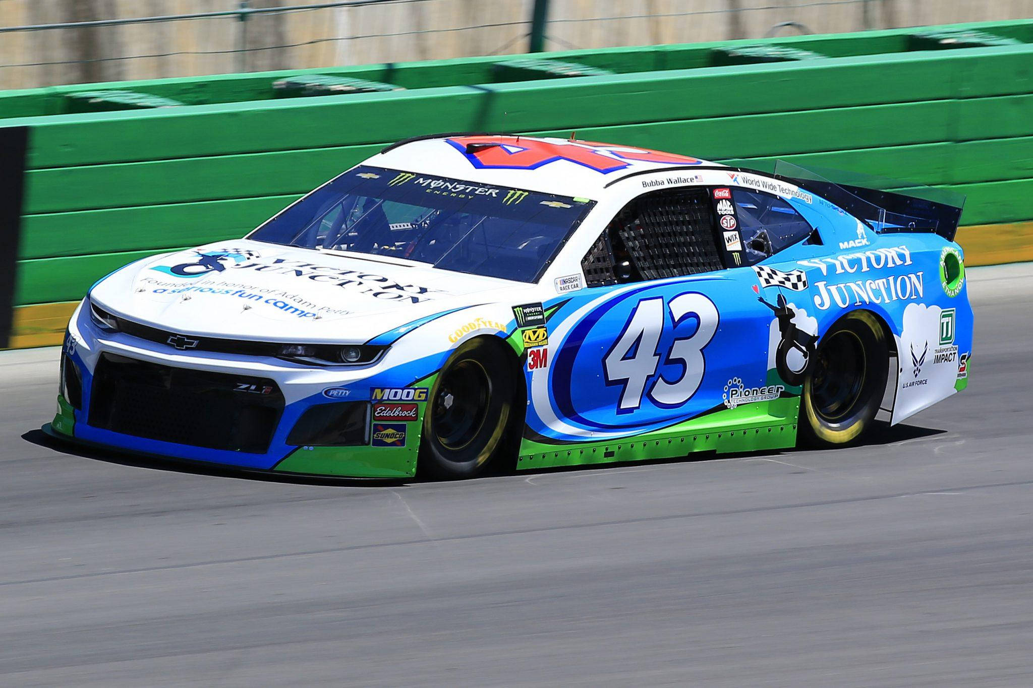 Bubba Wallace 桌布 壁紙 — 一輛藍白綠色的 #43 NASCAR 賽車在賽道上疾馳，帶有動態模糊效果，並可見贊助商貼紙。