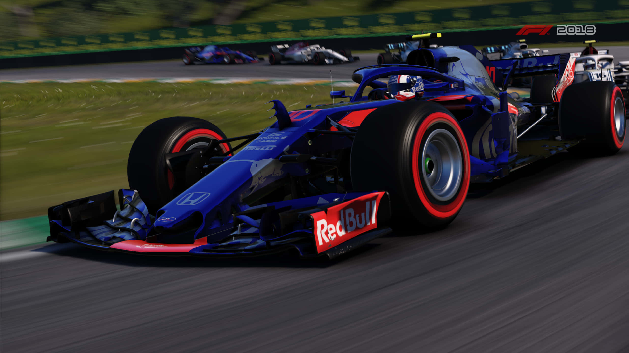 跑車 桌布 壁紙 — 一輛藍紅色的Red Bull Formula 1賽車在賽道上疾馳，背景是模糊的綠色草地和其他賽車。