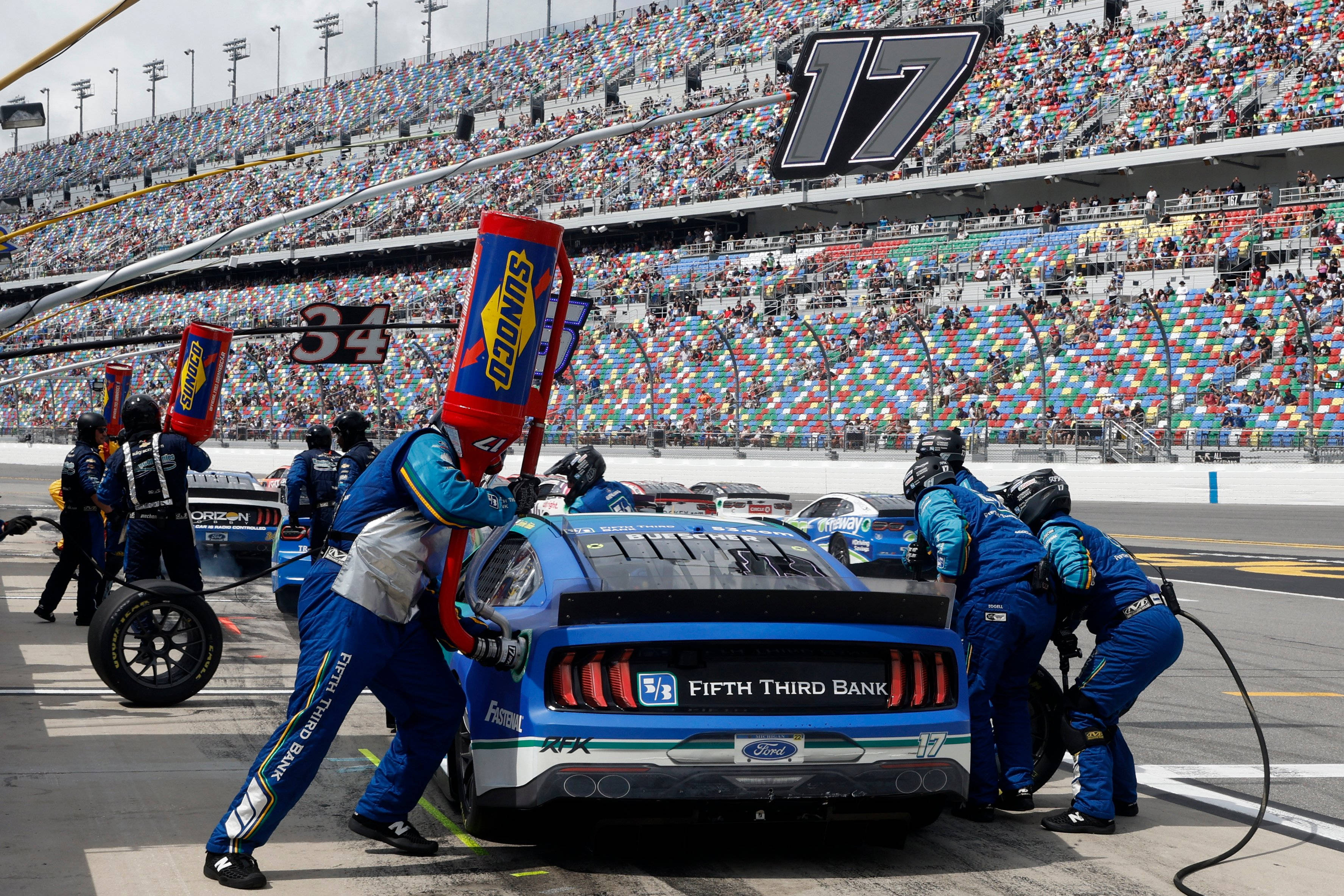Motorsport 桌布 壁紙 — 一輛藍色NASCAR賽車（號碼17）在日間比賽期間於座無虛席的體育館內由維修站人員進行維修。