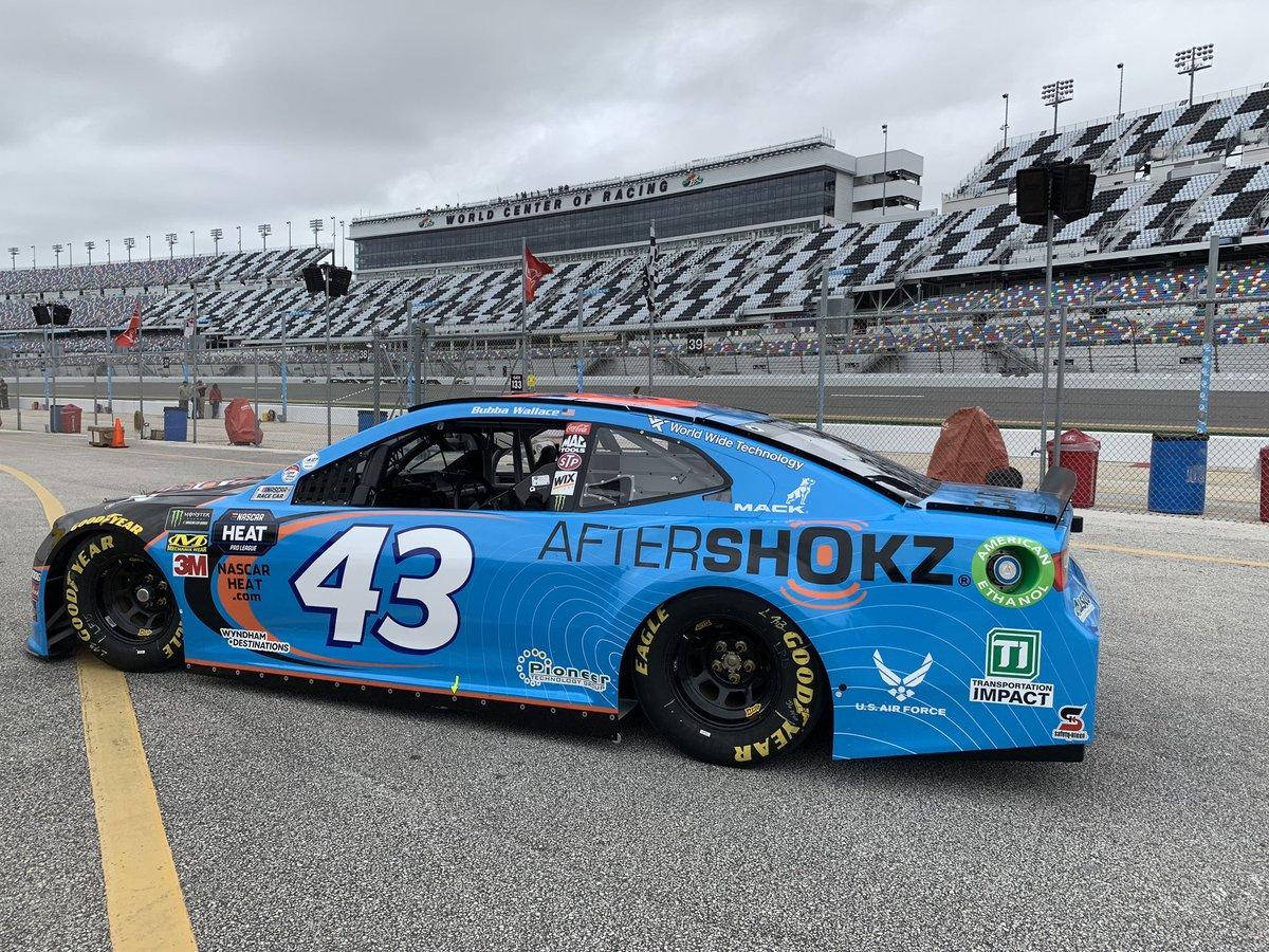Bubba Wallace 桌布 壁紙 — 一輛藍色NASCAR賽車，號碼43，停泊在賽道上，天空陰沉，背景是空無一人的看台。