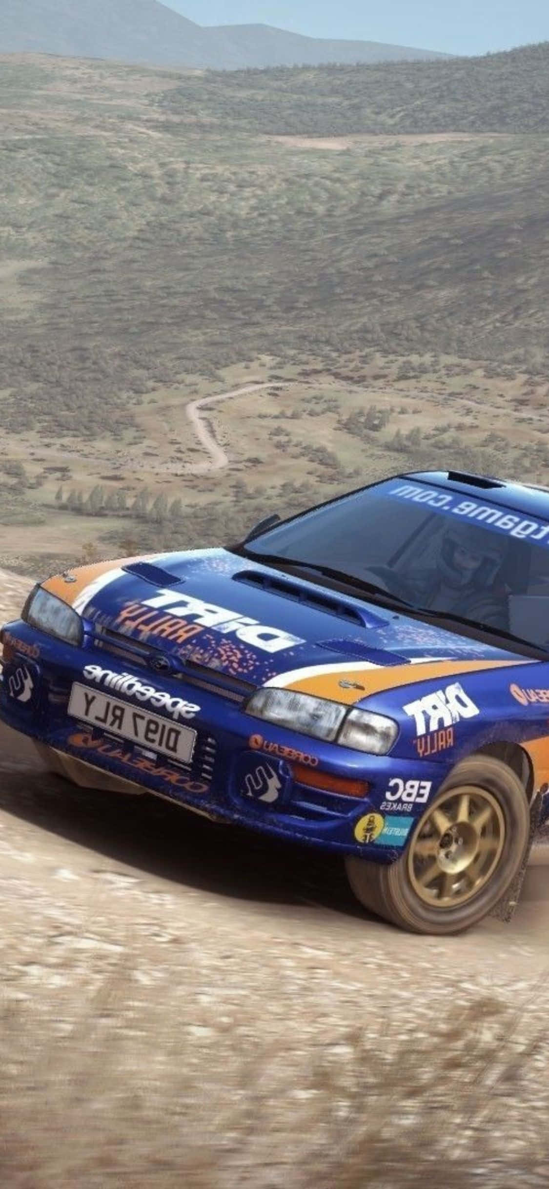 iPhone Xs Dirt Rally 桌布 壁紙 — 一輛藍色和橙色的拉力賽車在塵土飛揚的山路上飛馳，背景是崎嶇的山丘。