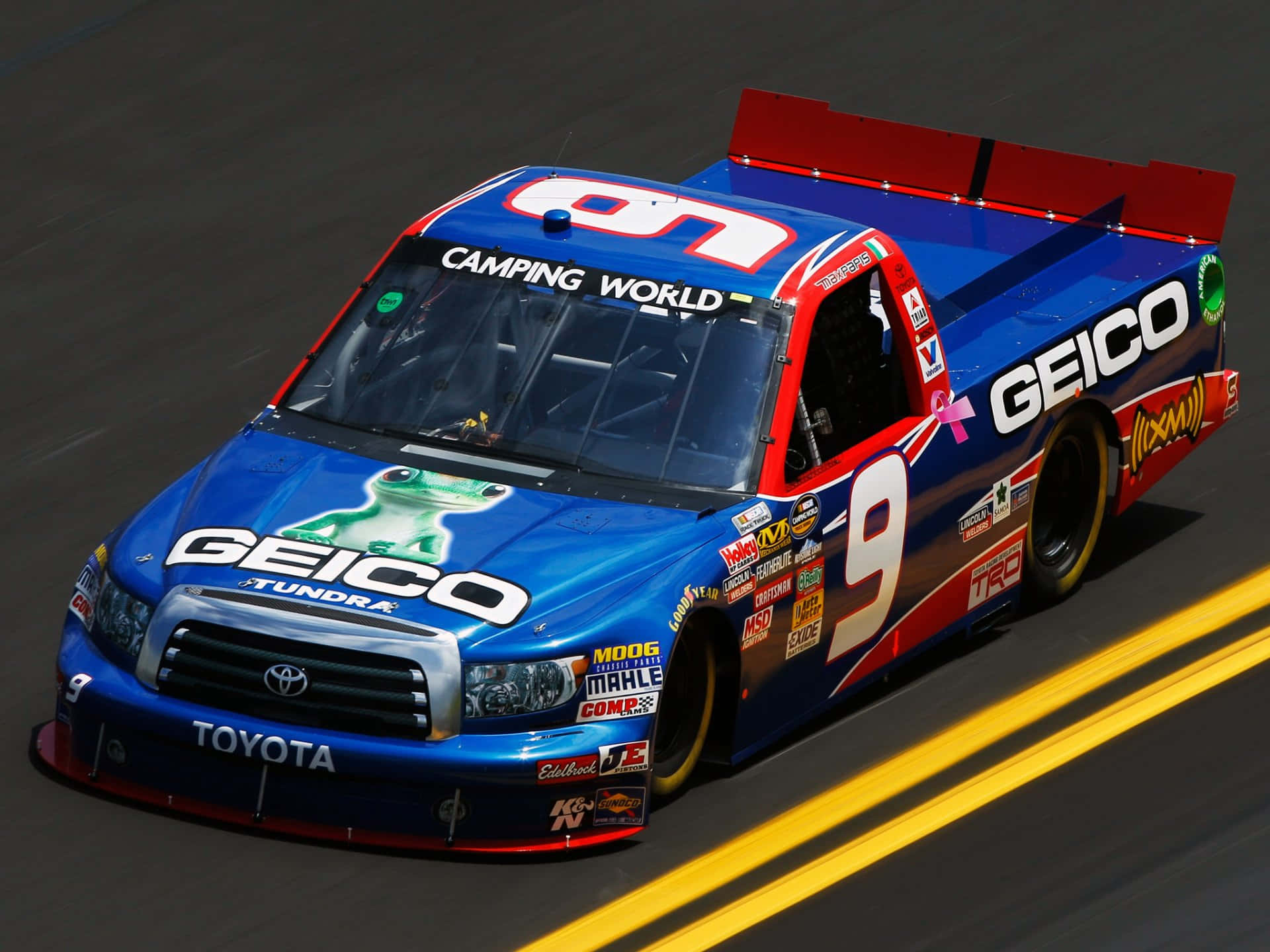 nascar 桌布 壁紙 — 一輛藍色和紅色的 #9 GEICO Toyota Tundra 賽車卡車在帶有黃色車道標記的賽道上飛馳。