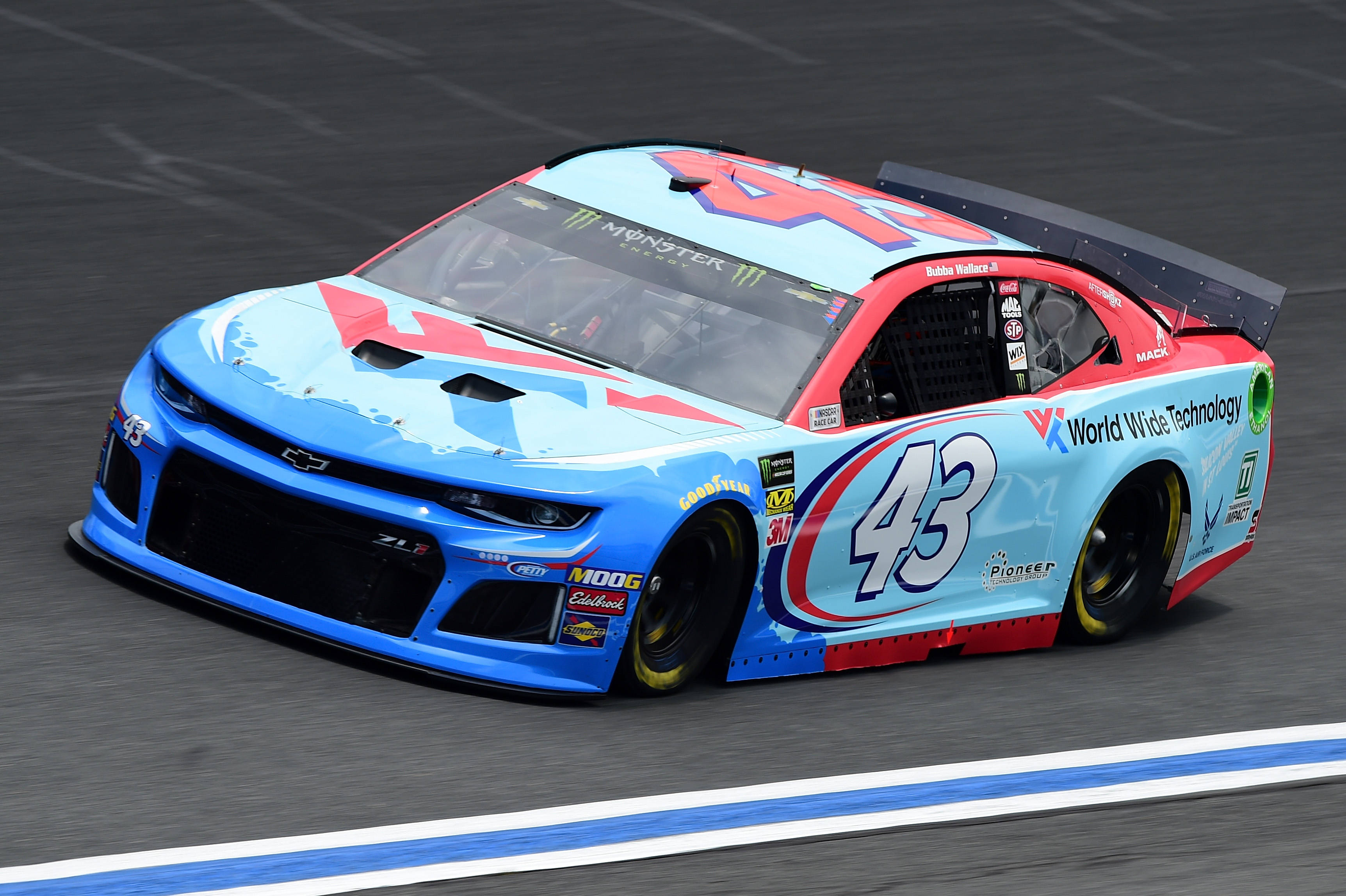 Bubba Wallace 桌布 壁紙 — 一輛藍色和紅色的NASCAR賽車，編號43，在明亮的日光下沿著賽道飛馳。