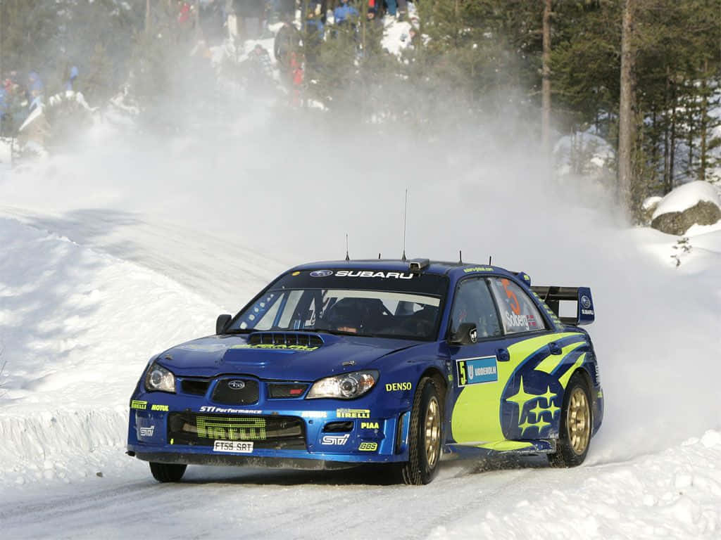 Ice Racing 桌布 壁紙 — 一輛藍色和萊姆綠色的Subaru拉力賽車在白雪覆蓋的森林山路中飛馳，揚起雪花。