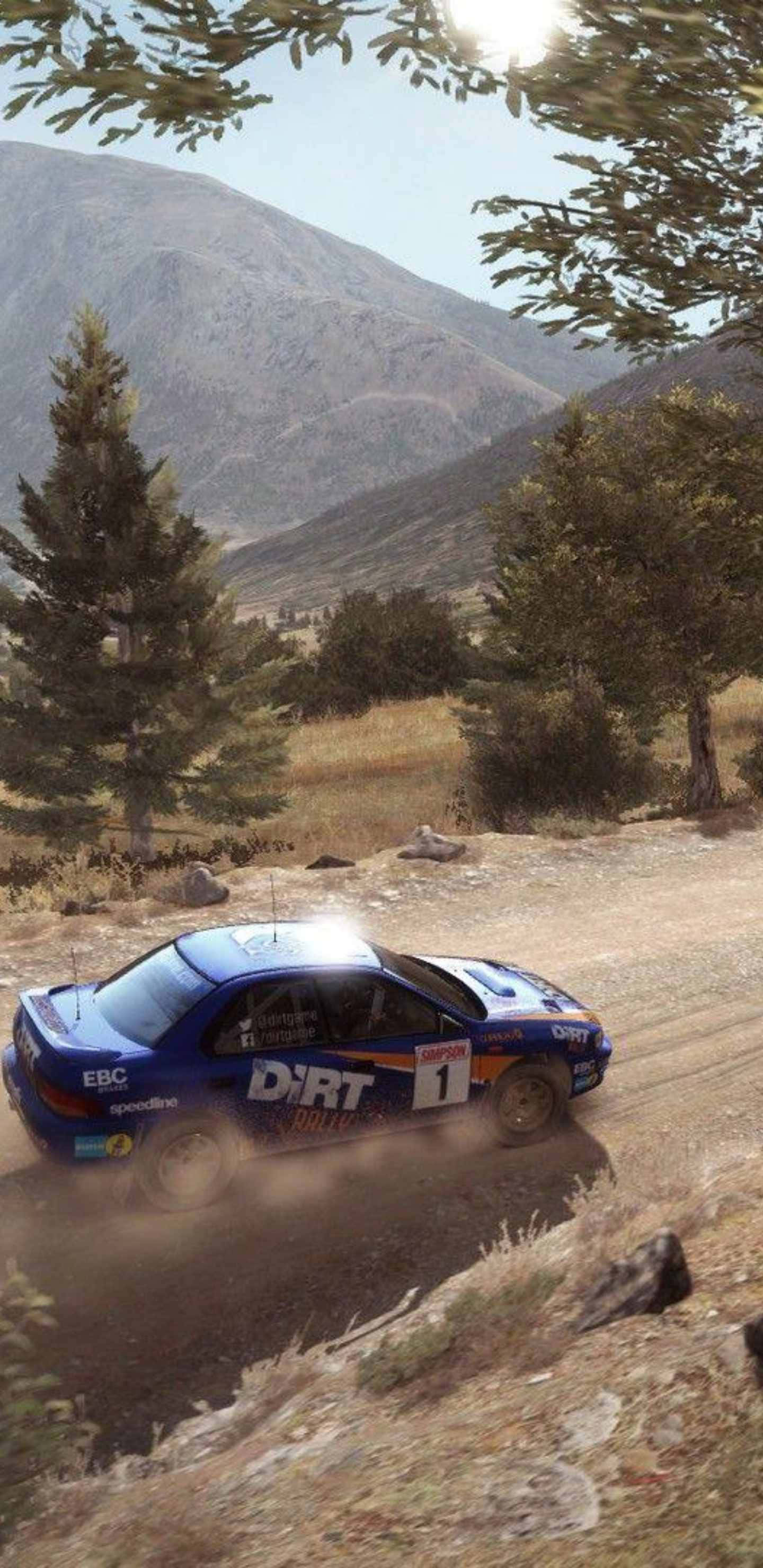 Android Dirt Rally 桌布 壁紙 — 一輛藍色拉力賽車在崎嶇的山地泥路上疾馳，揚起塵土，兩旁是松樹和岩石地形。
