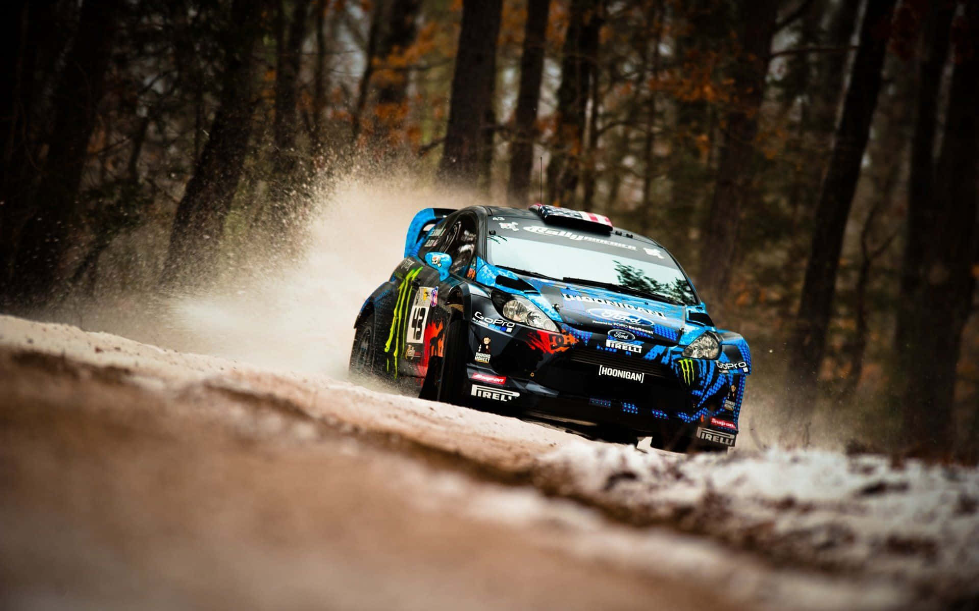 Ice Racing 桌布 壁紙 — 一輛藍色拉力賽車在秋天的森林泥路上疾馳，揚起灰塵和泥濘。