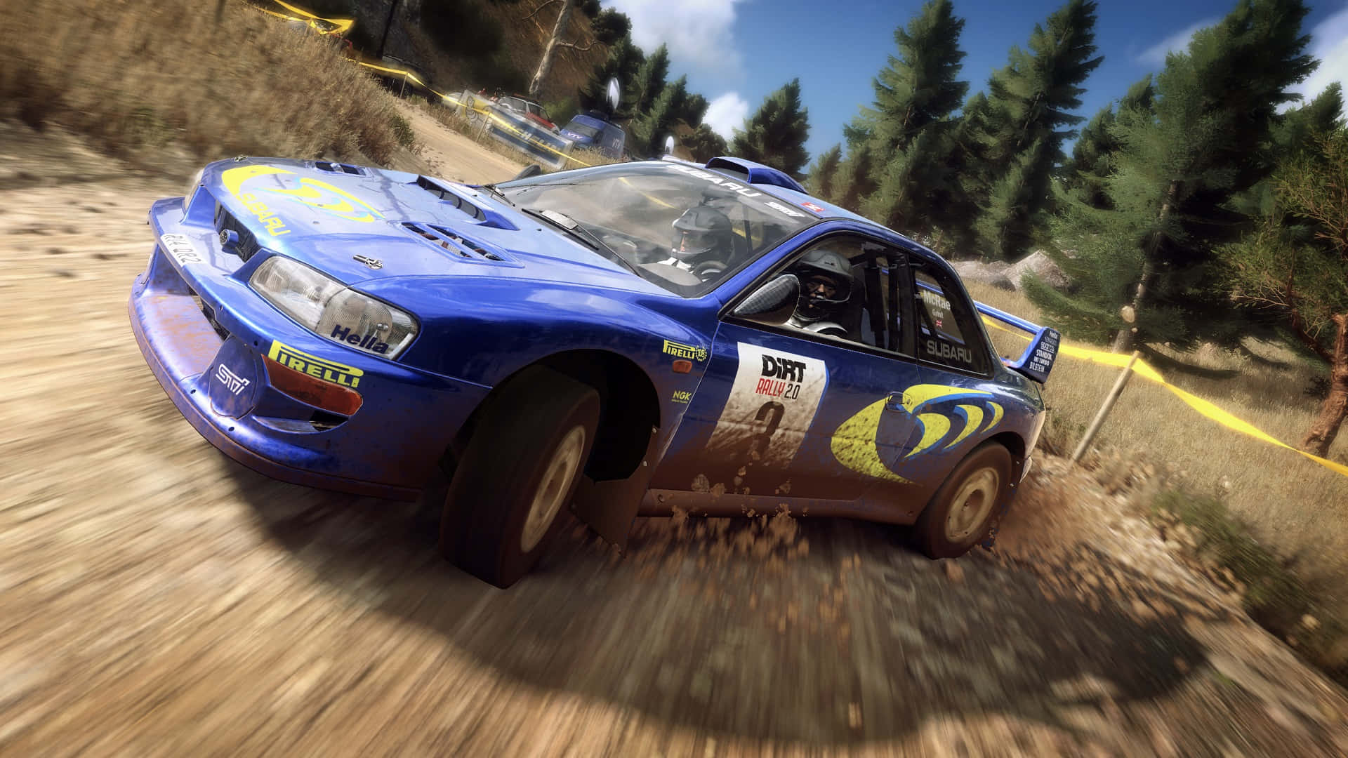 1920x1080 Dirt Rally 桌布 壁紙 — 一輛藍色的Subaru拉力賽車在明亮的天空下，在森林中的泥濘賽道上高速行駛，揚起灰塵。