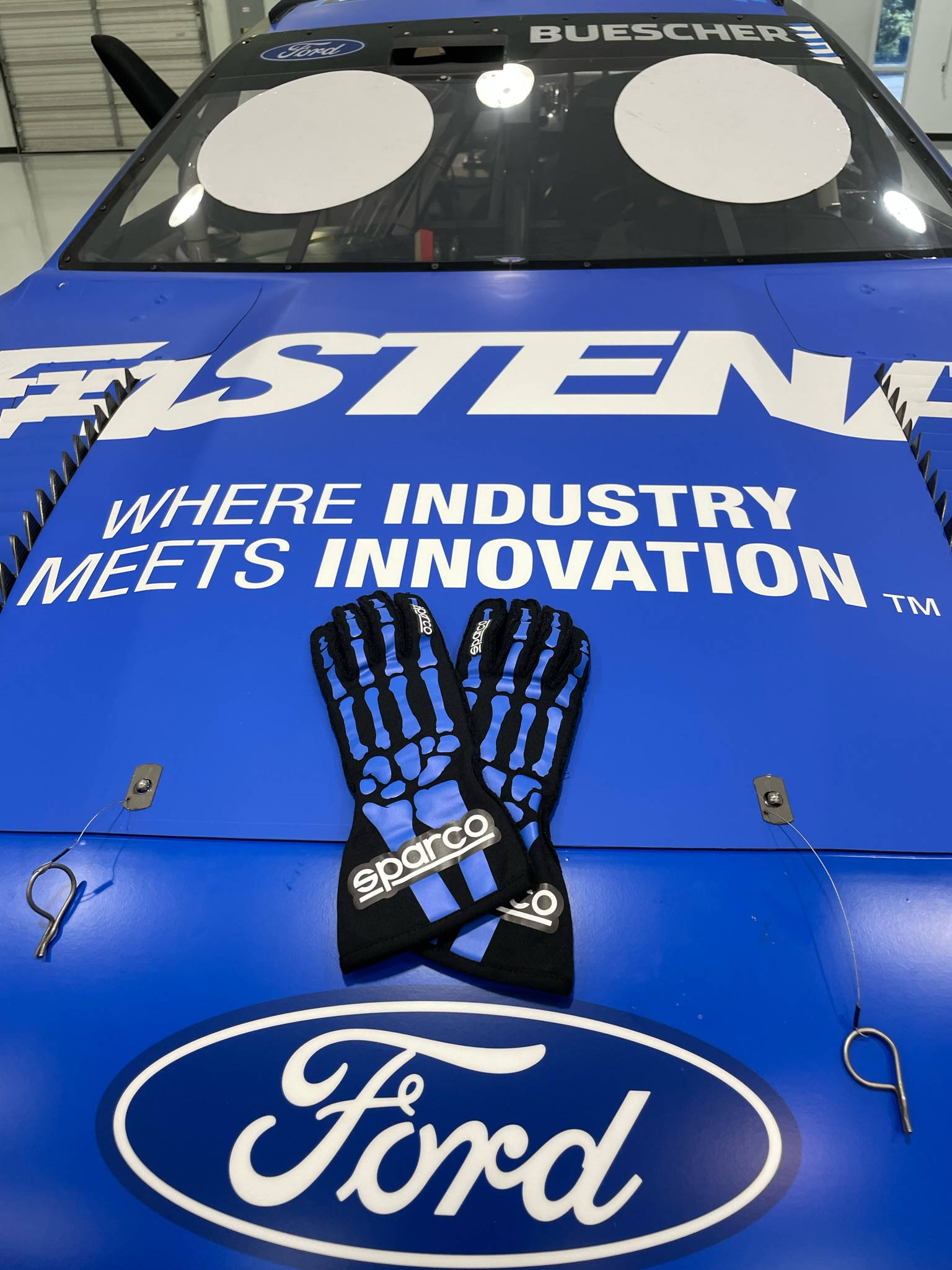 福特 桌布 壁紙 — 一輛藍色福特賽車，上面有「FASTEN」和「WHERE INDUSTRY MEETS INNOVATION」文字，黑色Sparco賽車手套放在引擎蓋上。