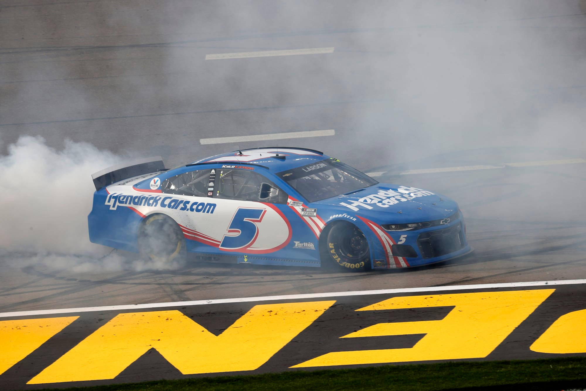 Kyle Larson 桌布 壁紙 — 一輛藍色賽車，號碼5，在賽道上進行戲劇性的燒胎，冒出濃煙。